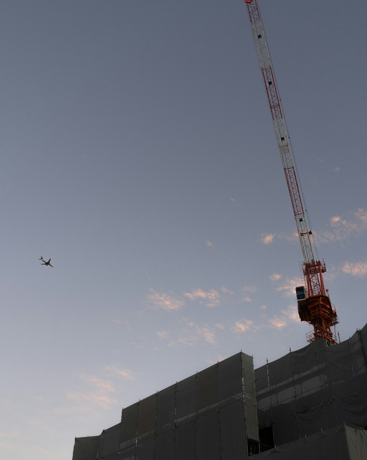 黄昏天空下的建筑工地与起重机和无人机