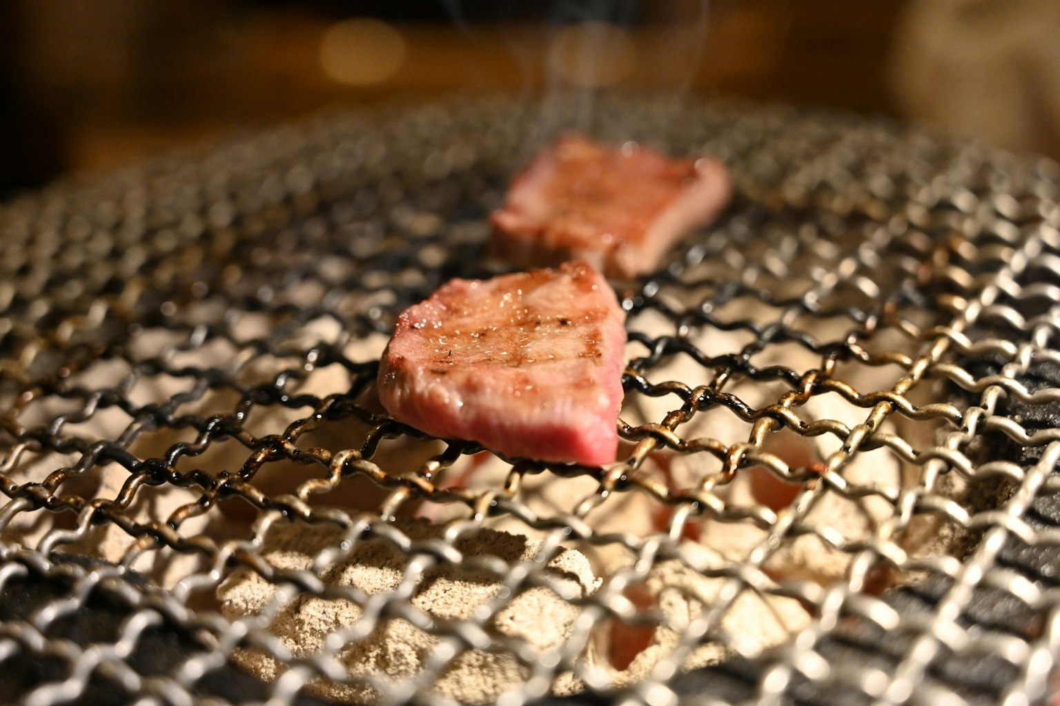 Slices of meat grilling on a wire mesh grill