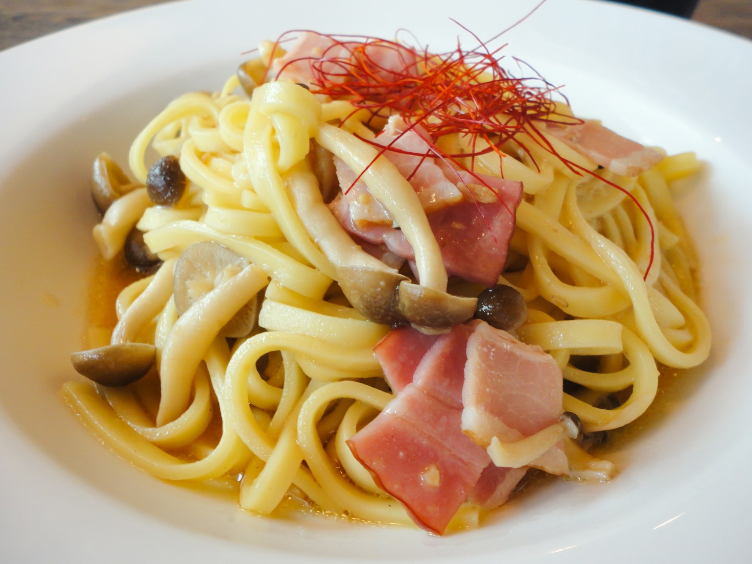 Pasta cremosa guarnita con prosciutto e funghi