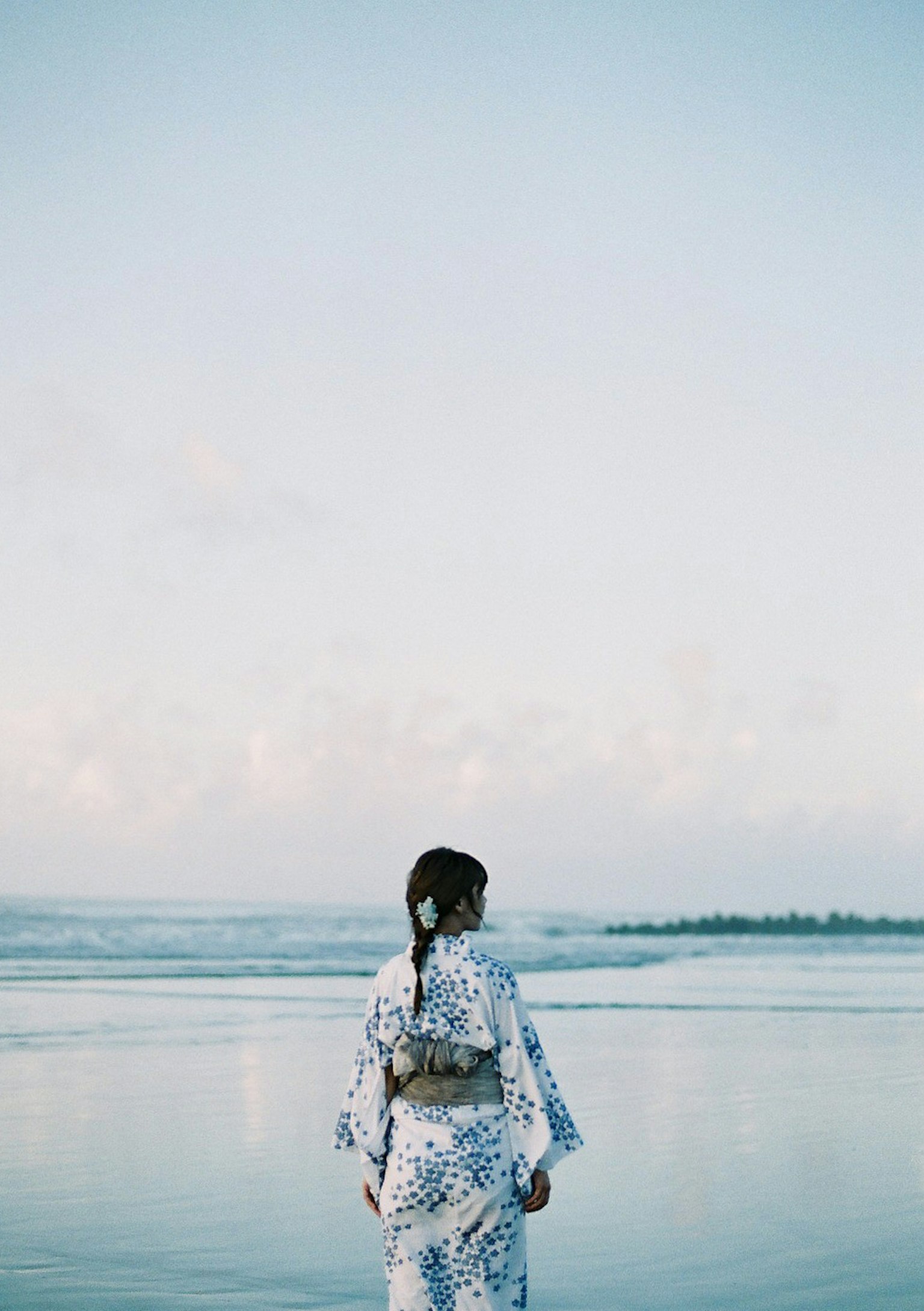A woman in a kimono standing by the seaside