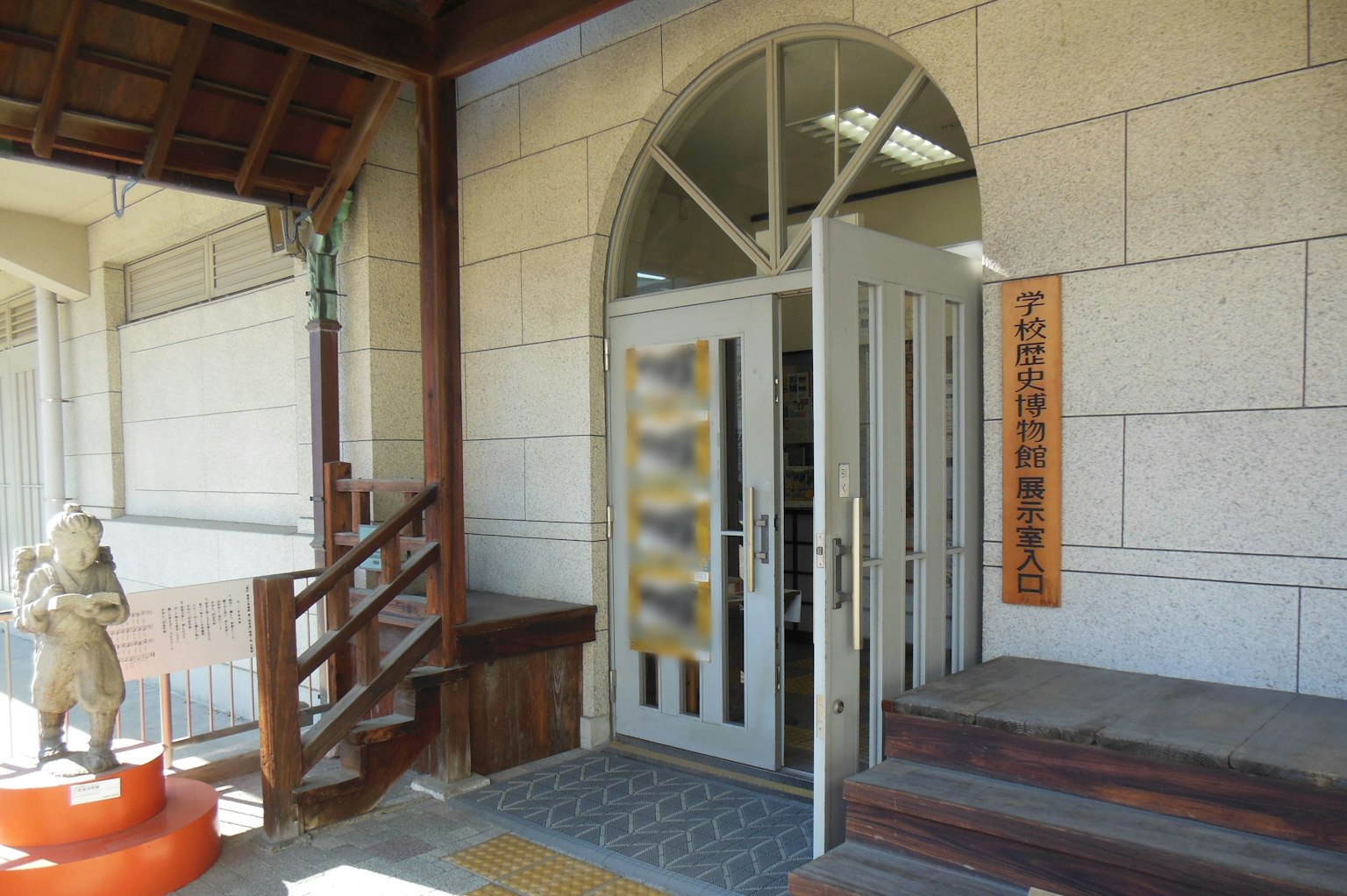 Vue extérieure d'une entrée de bâtiment avec des portes en verre et un panneau