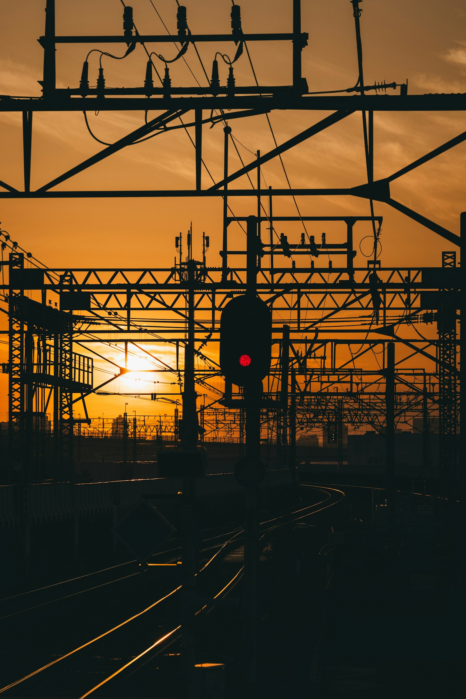 Silhouette of railway signal and overhead wires against a sunset