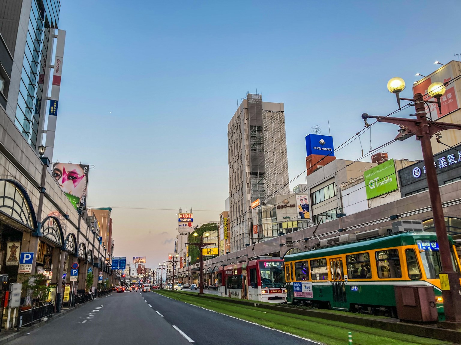 รถรางและอาคารตามถนนในเมืองในช่วงพลบค่ำ