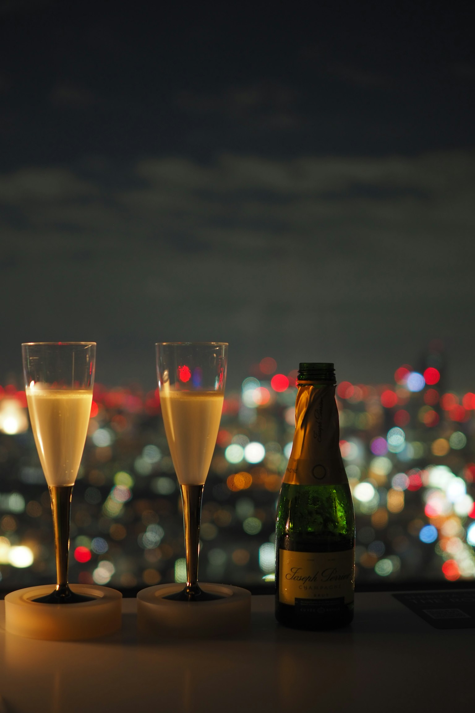Bicchieri di champagne e bottiglia con skyline notturno