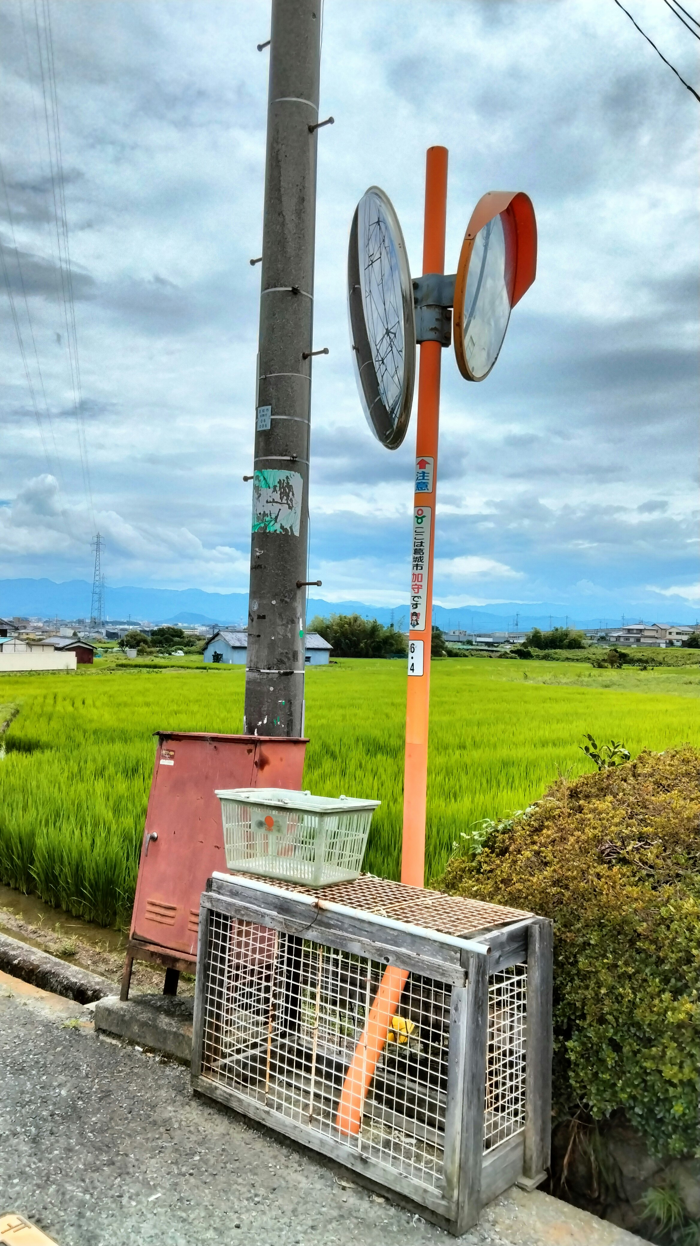 田園の道沿いにある電柱と回転式の標識、空に雲