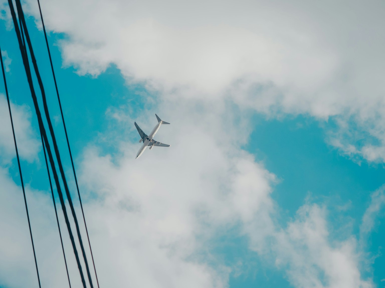 Avion volant dans un ciel bleu avec des nuages et des lignes électriques