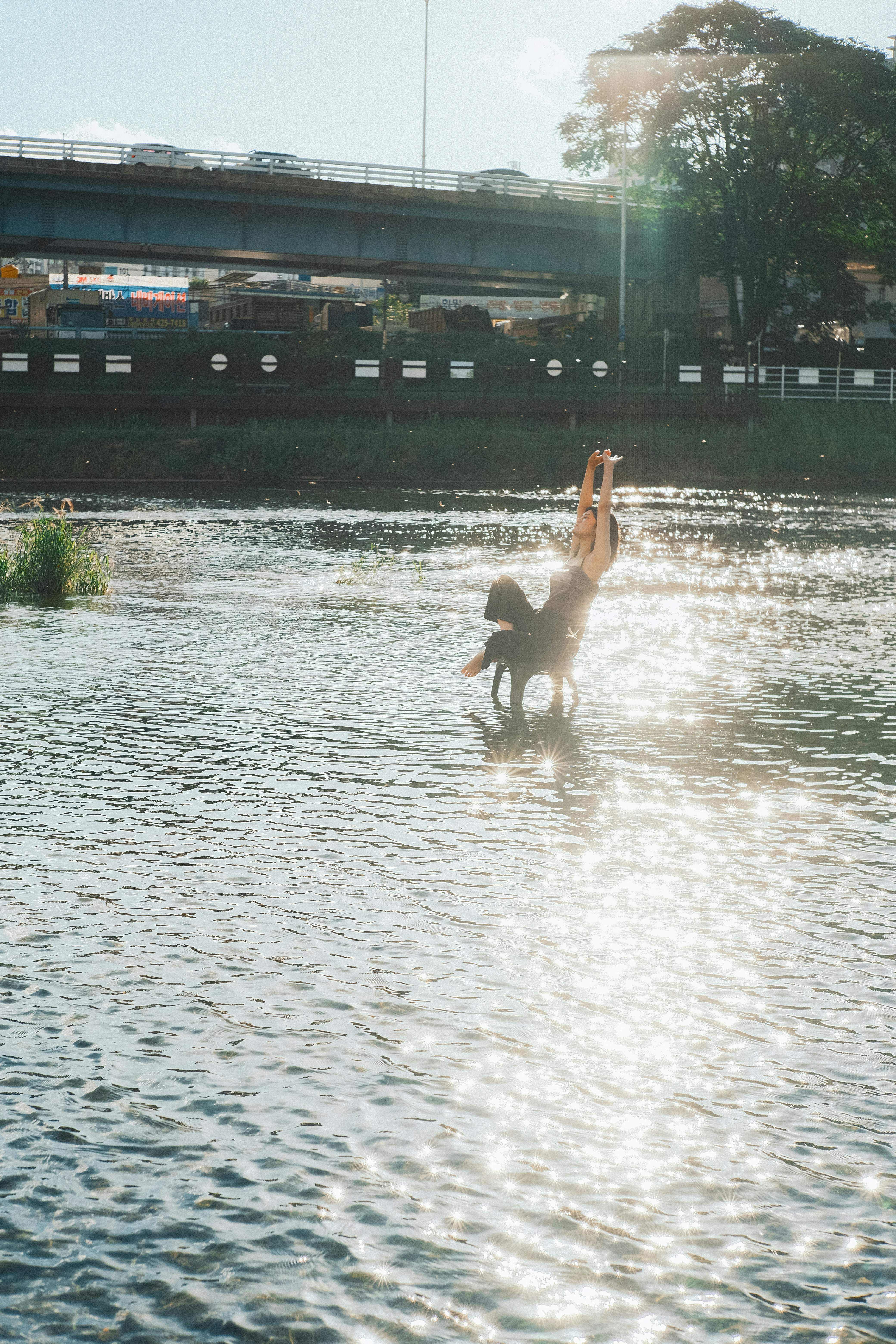 川辺で水しぶきを上げる人と夕方の光のきらめき