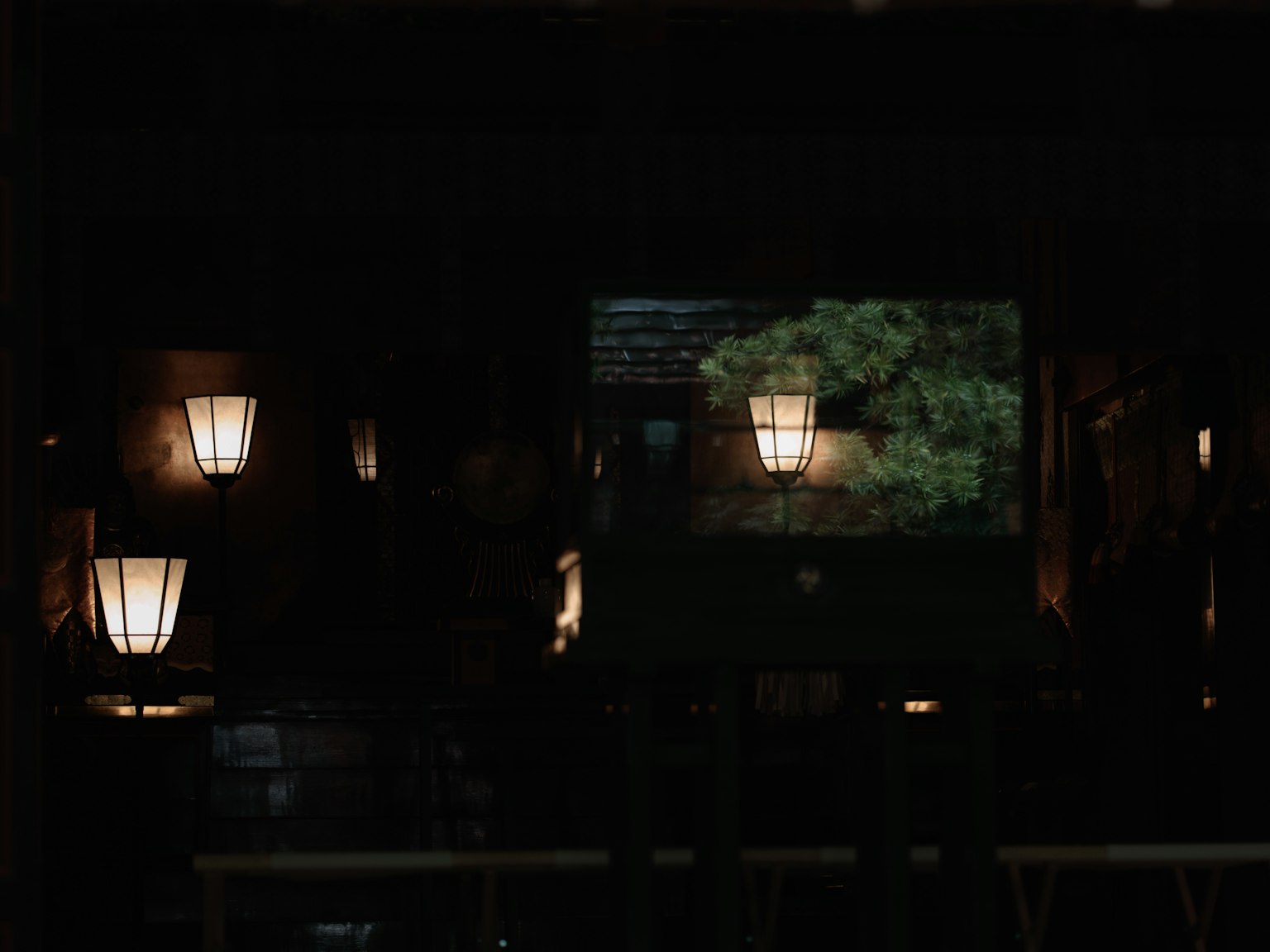 Traditionelle japanische Laternen leuchten vor einem dunklen Hintergrund mit Blick auf grüne Bäume