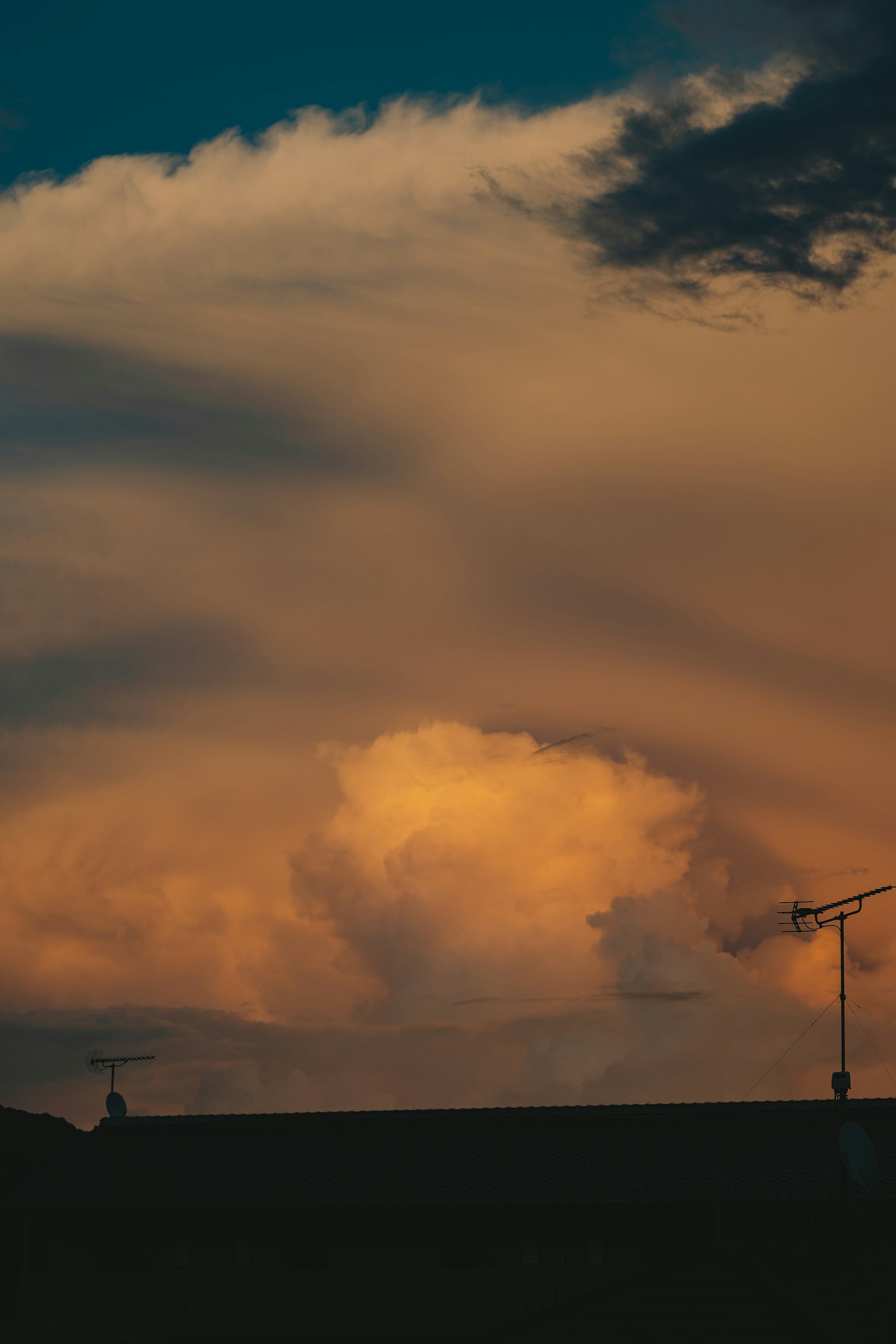 Silhouette de toits contre un ciel de coucher de soleil avec des nuages vibrants