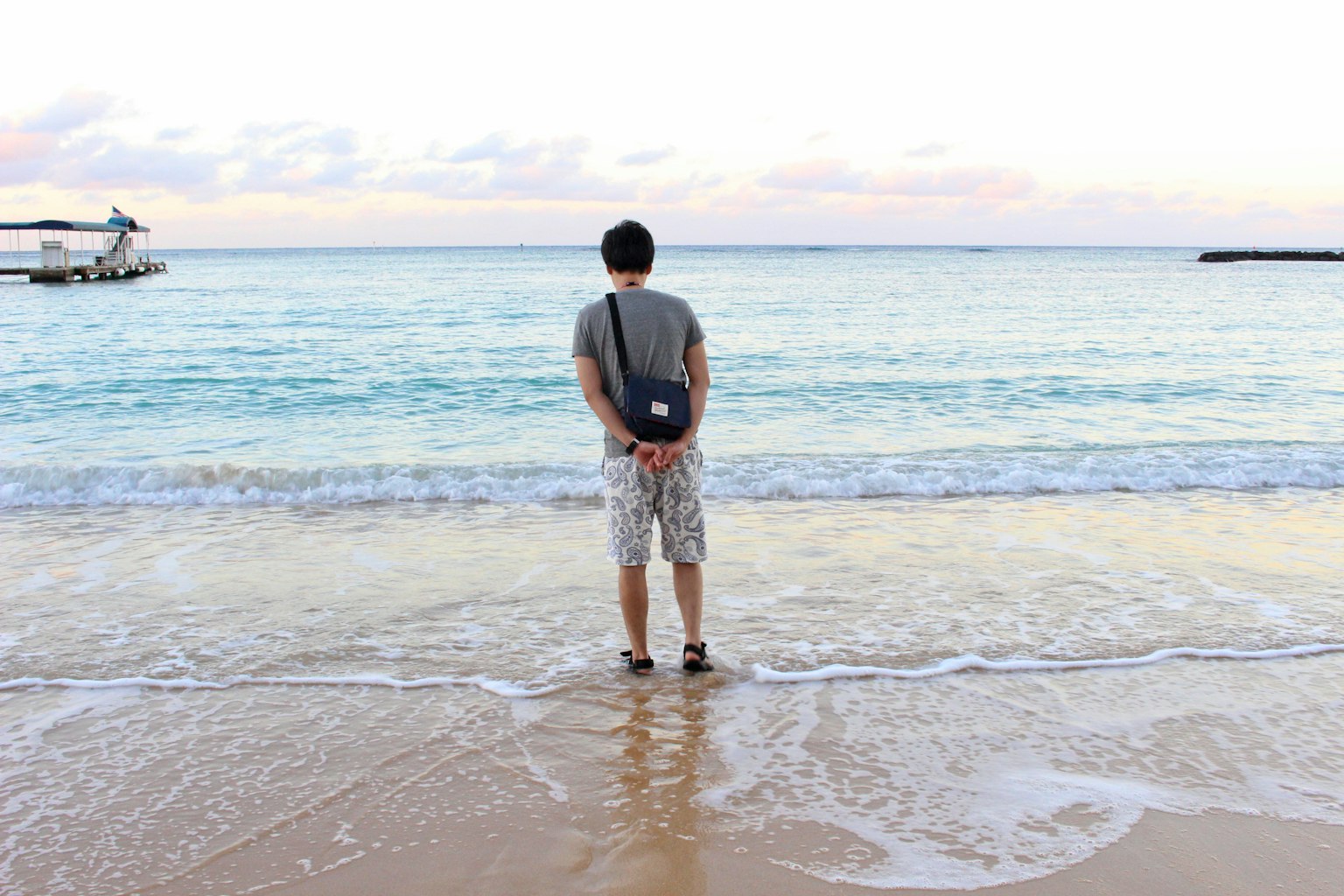 一个男人站在海滩上，波浪拍打着他的脚