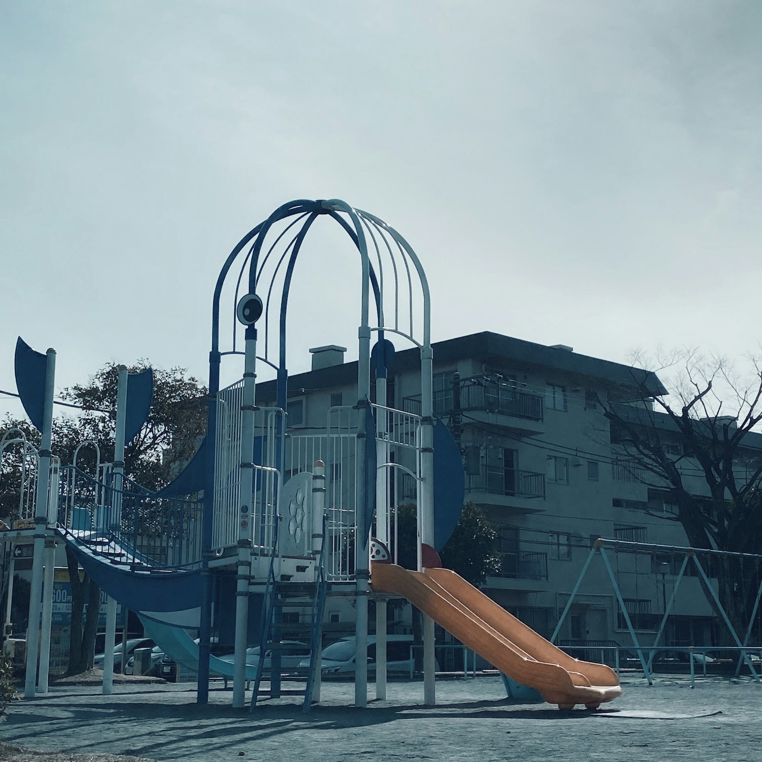 Parque infantil con tobogán y equipo de juego edificio al fondo