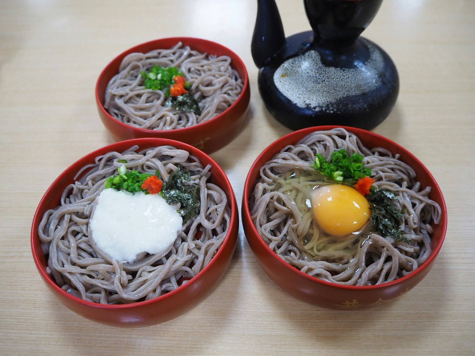 สามชามบะหมี่โซบะที่มีท็อปปิ้งเช่นไข่และผัก