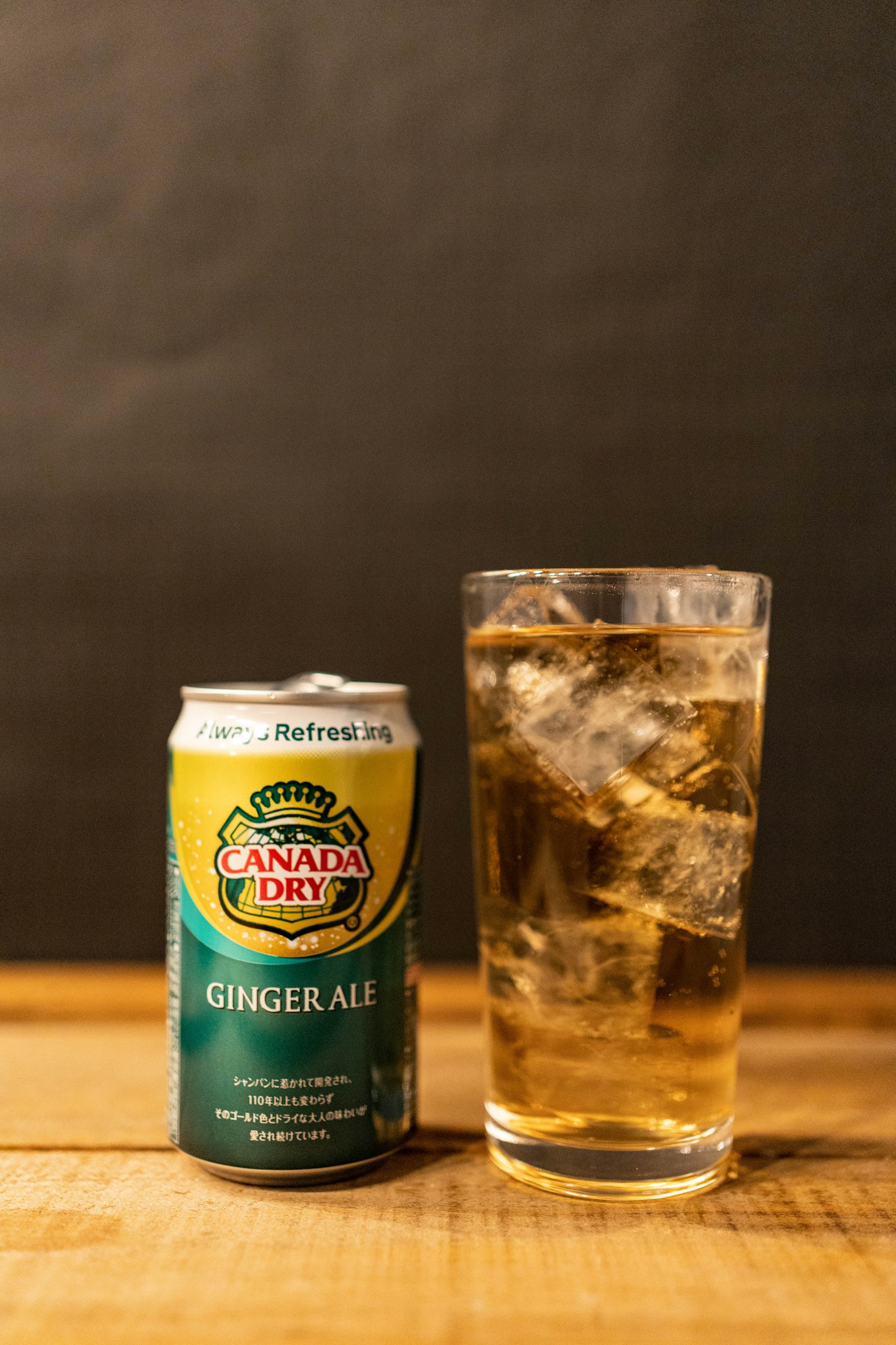 Eine Dose Ingwerbier und ein Glas mit Eis auf einem Holztisch
