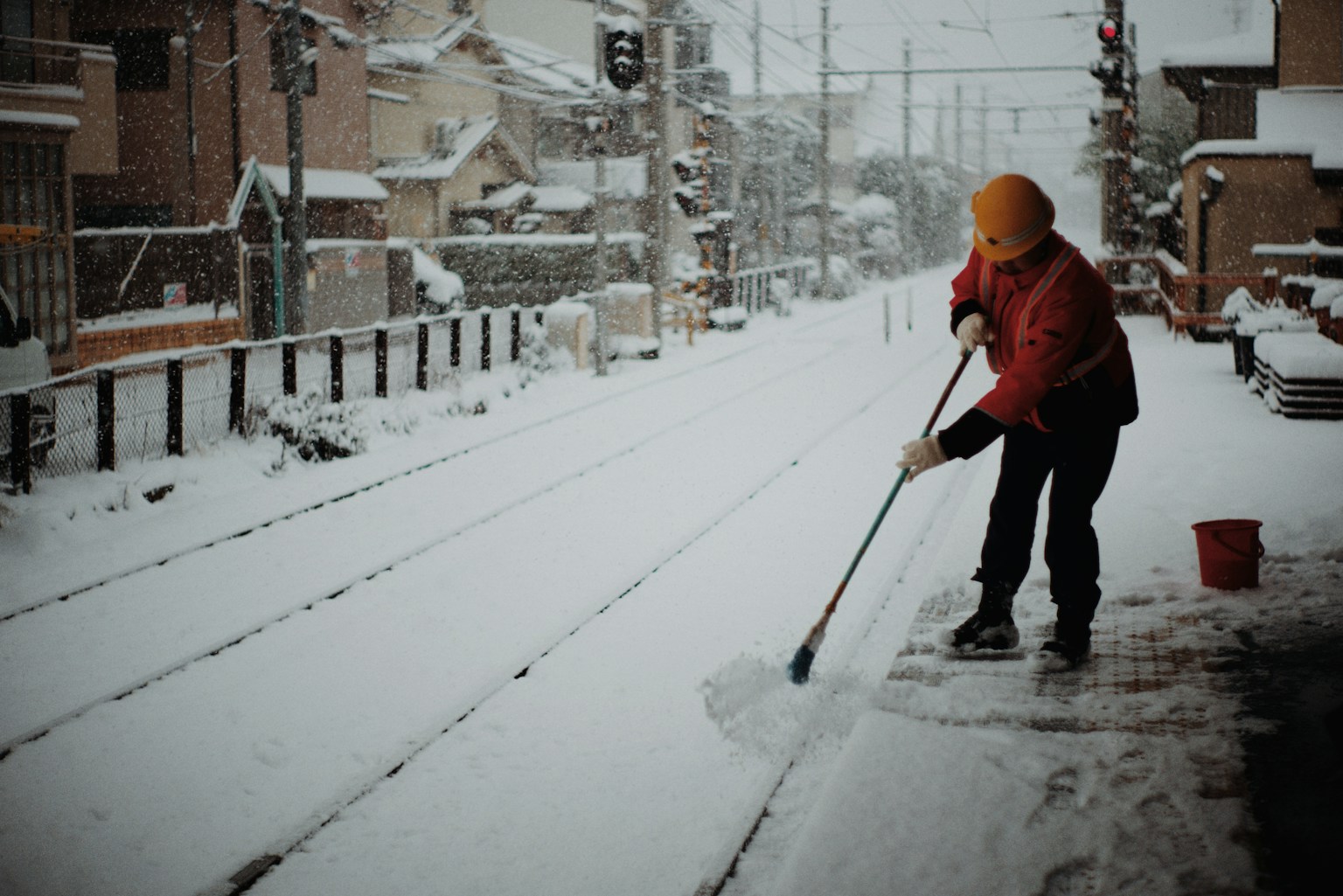 A worker clearing snow from train tracks in a winter scene