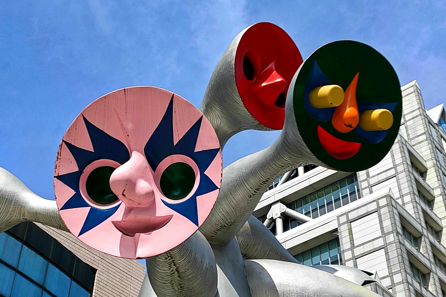 Escultura única con caras coloridas bajo un cielo azul