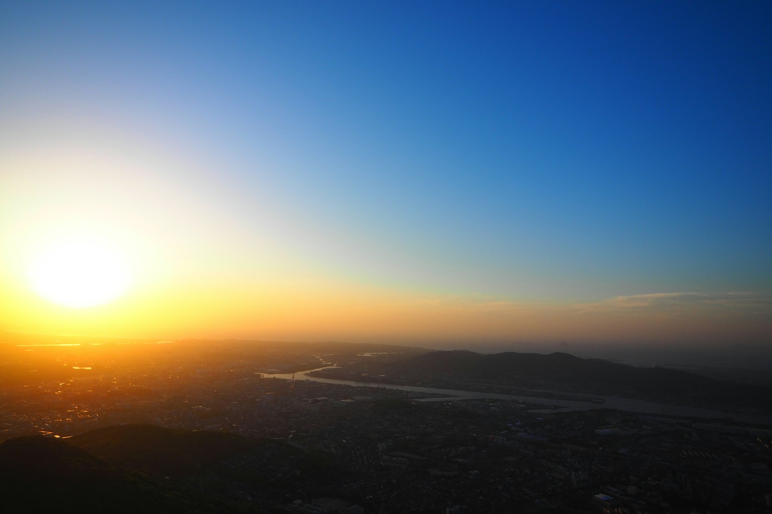 Sunset over a river with a gradient blue sky