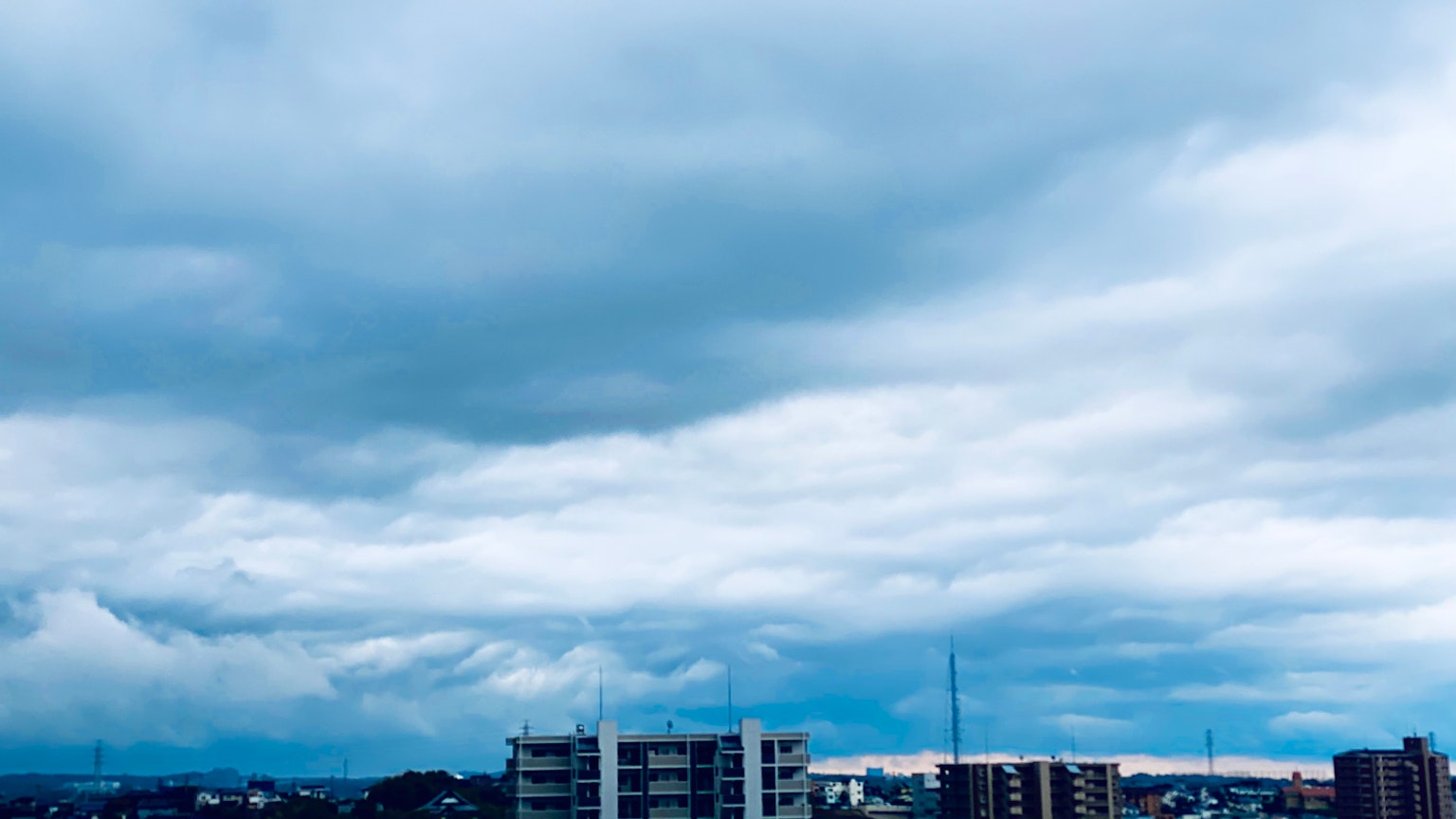 Cảnh quan đô thị dưới bầu trời nhiều mây với các tòa nhà và tháp radio