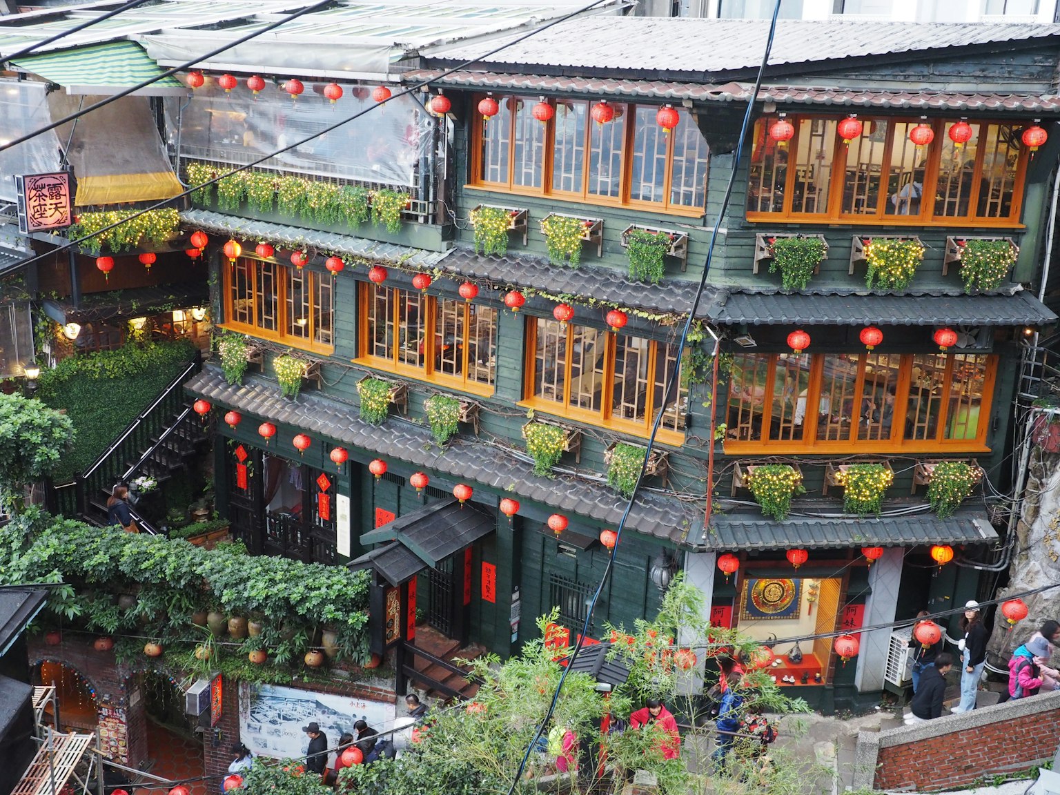 Bâtiment traditionnel taïwanais orné de lanternes rouges avec des balcons fleuris et une rue animée