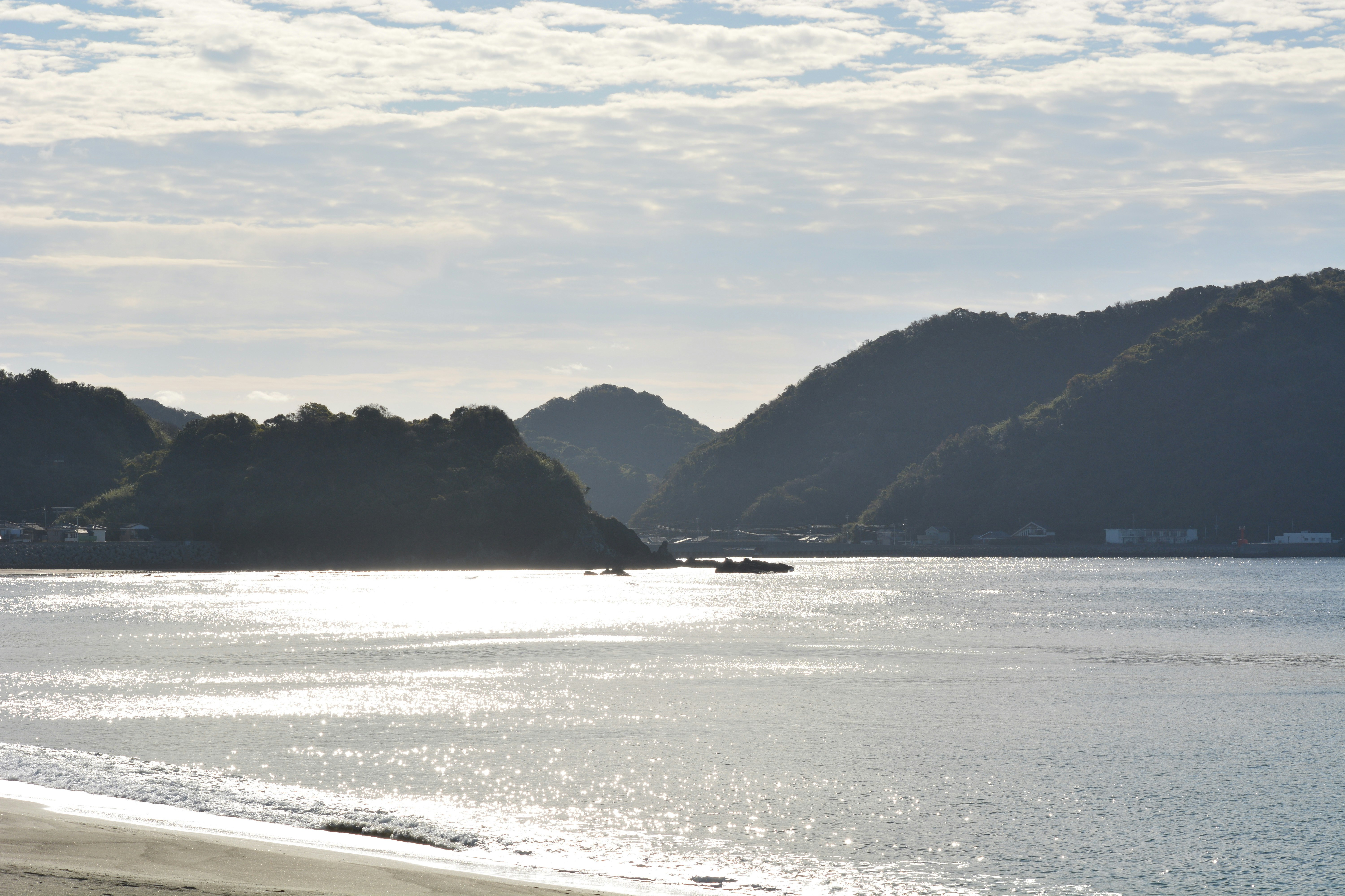 海辺の砂浜と穏やかな入江、山並みを望む景色