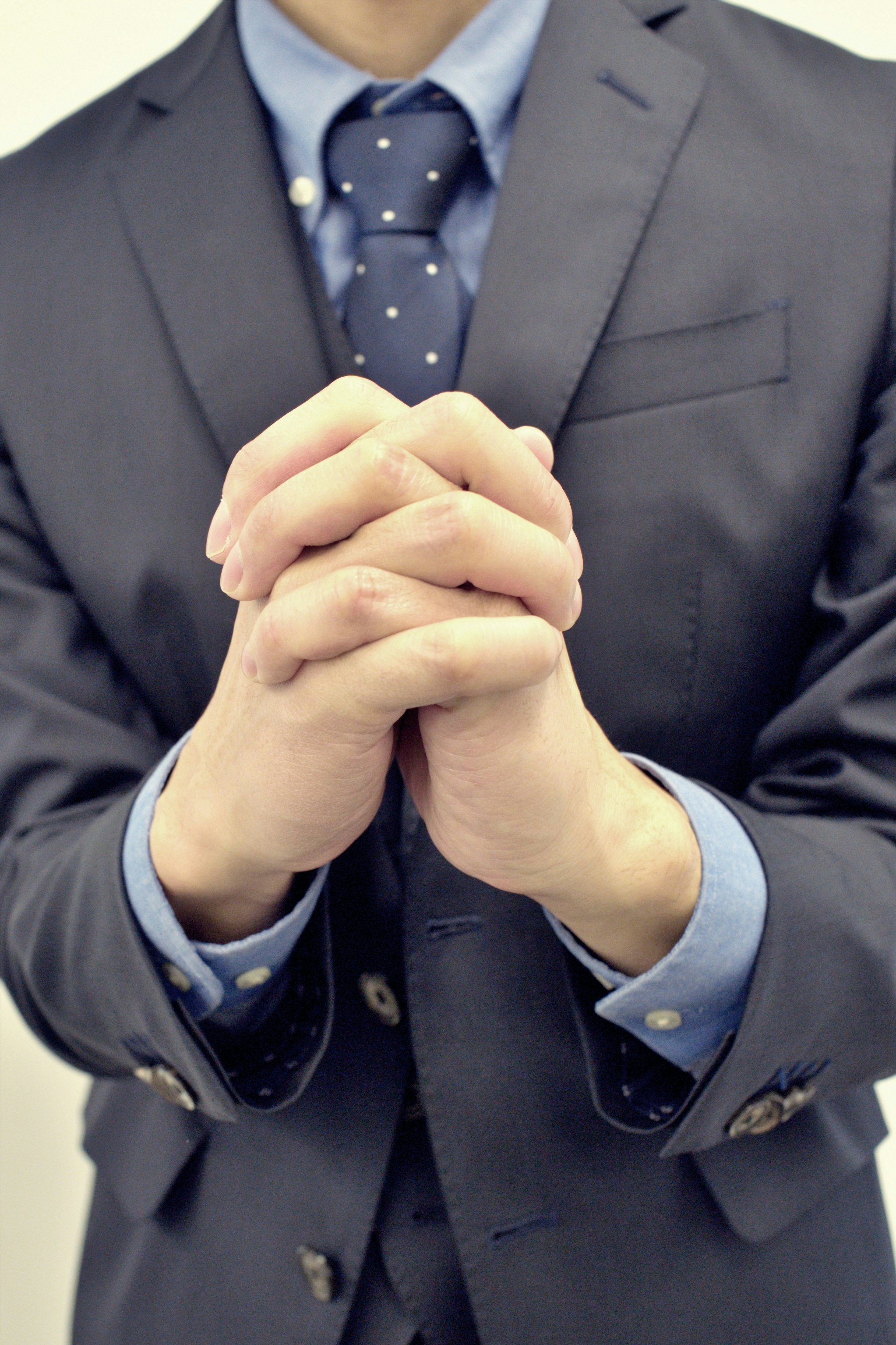 Business man in a suit clasping his hands