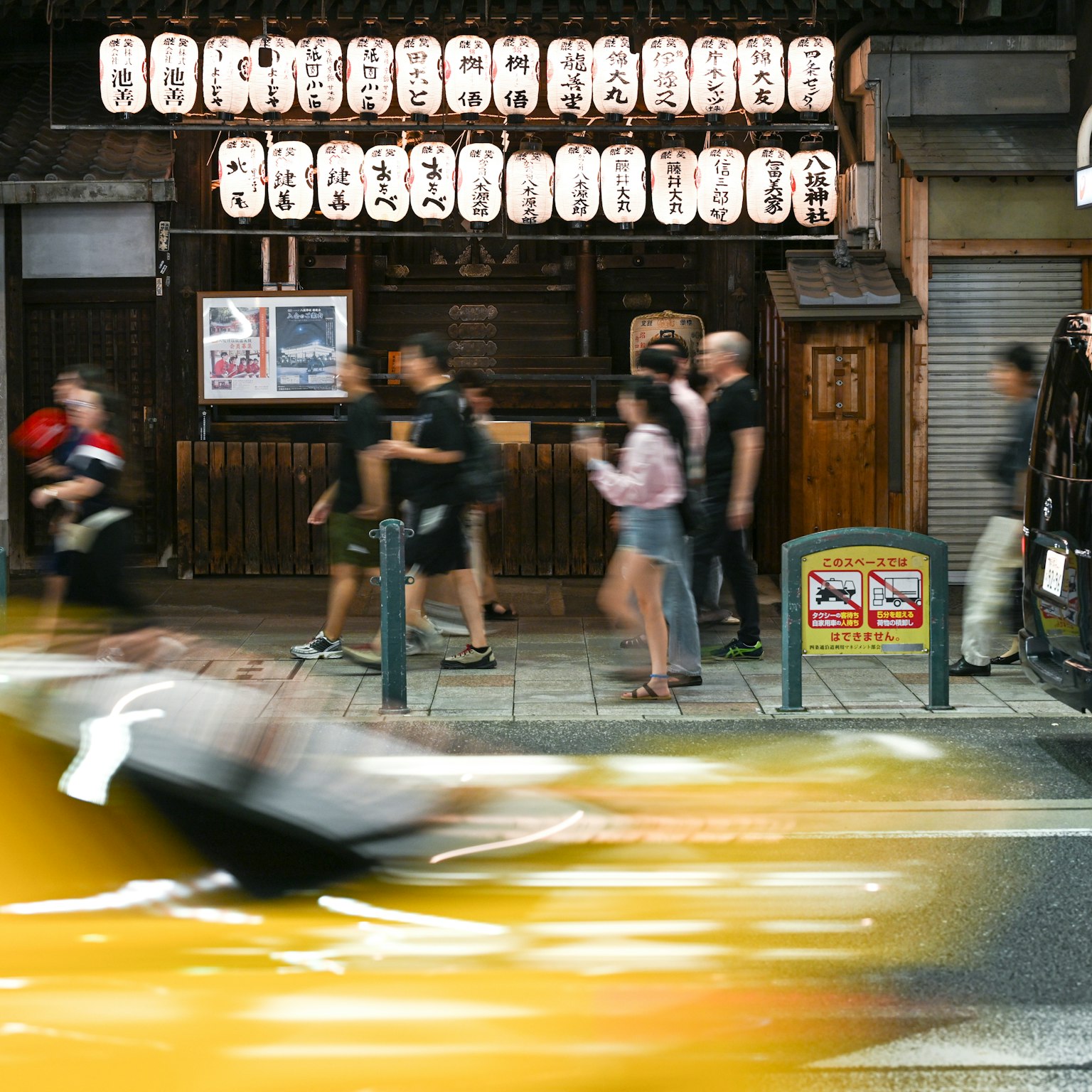 Busy street with people walking and traditional building adorned with lanterns