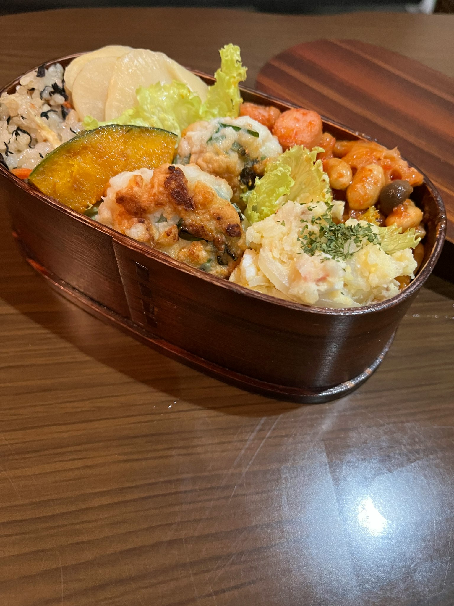 Hộp bento gỗ chứa nhiều món ăn và cơm