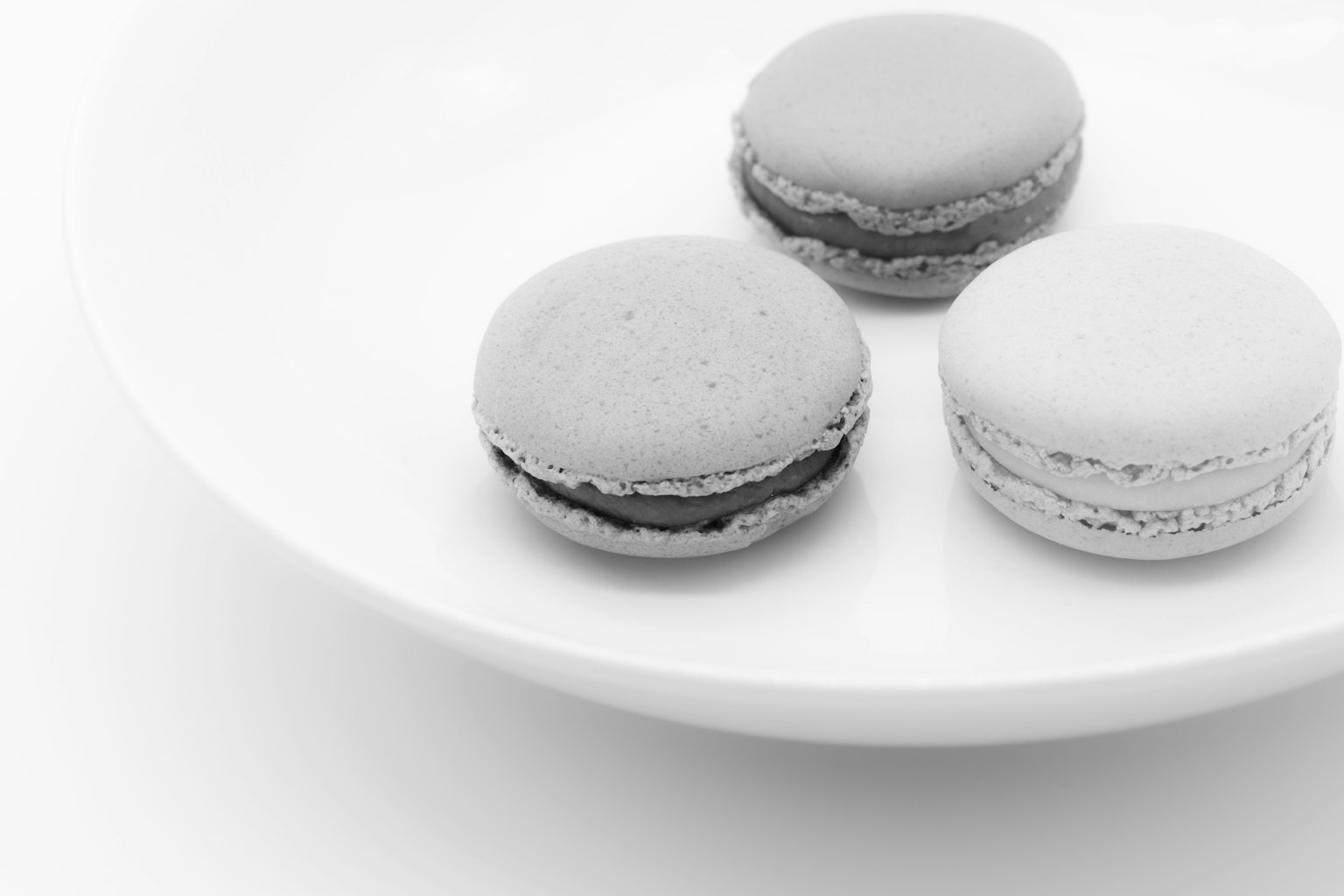 Trois macarons monochromes sur une assiette blanche