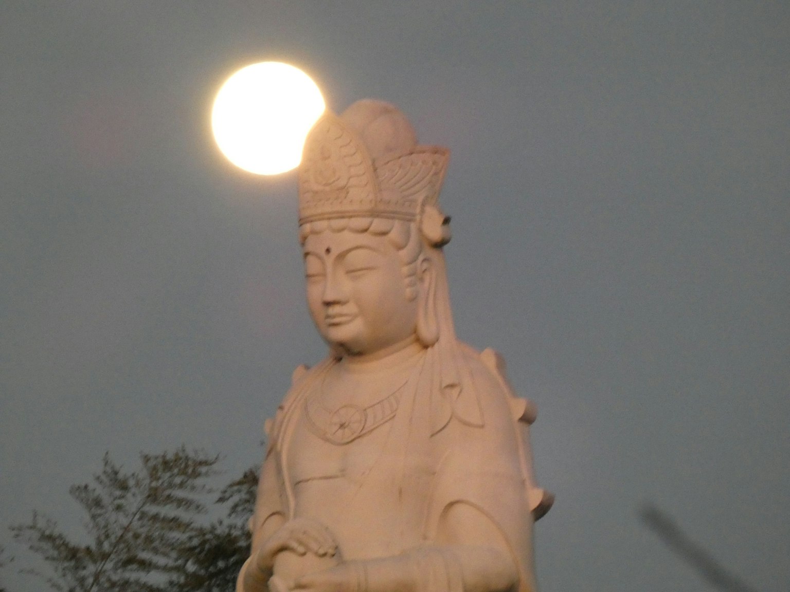 Bella scultura di una figura buddista con la luna sopra