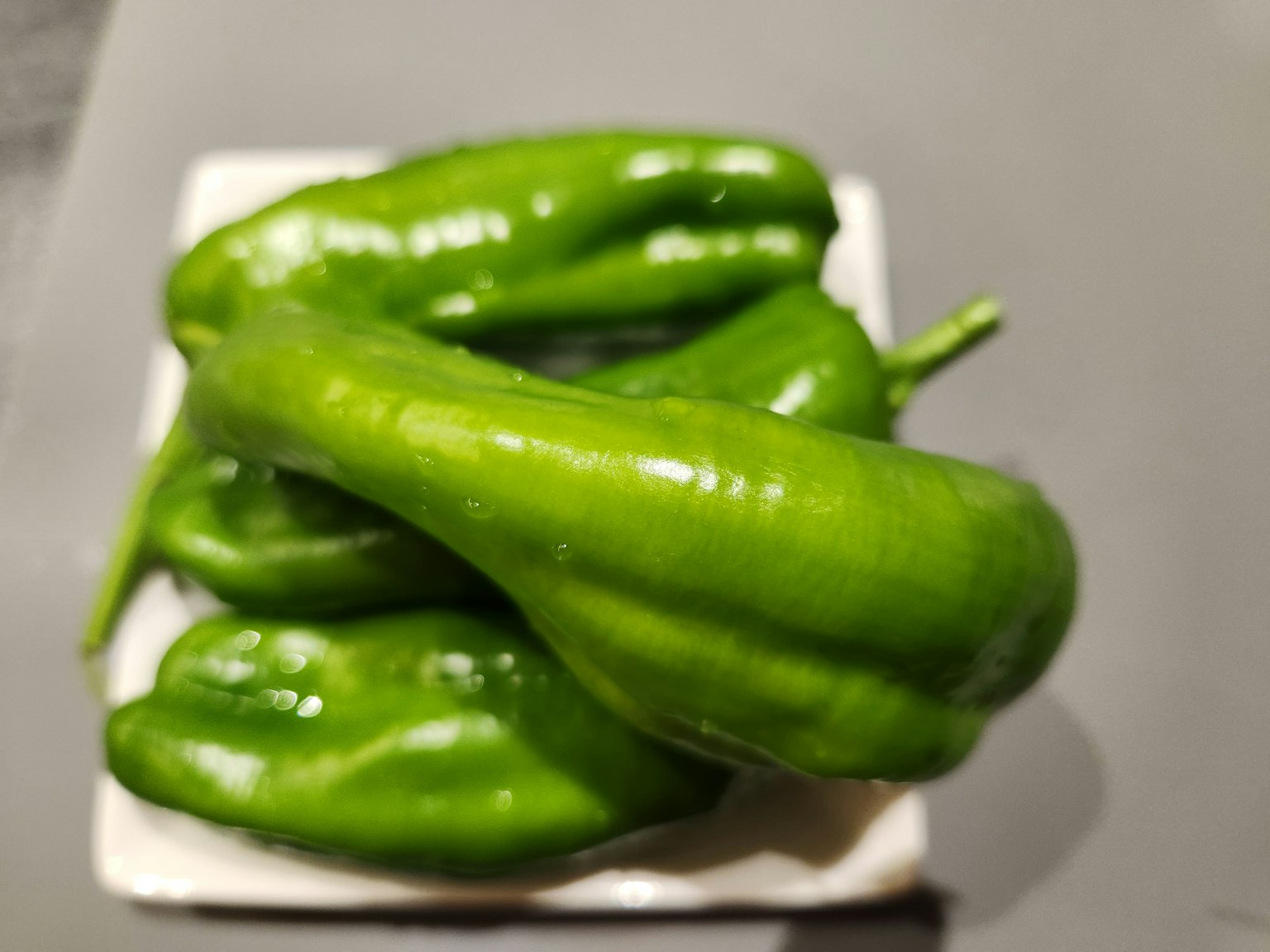 Eine Gruppe grüner Paprika auf einem weißen Teller angeordnet