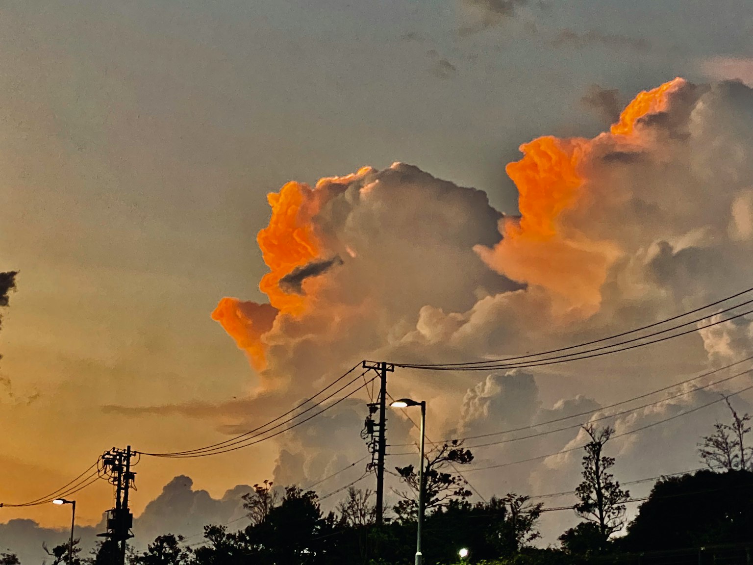 Nuages au coucher de soleil avec des lampadaires au premier plan