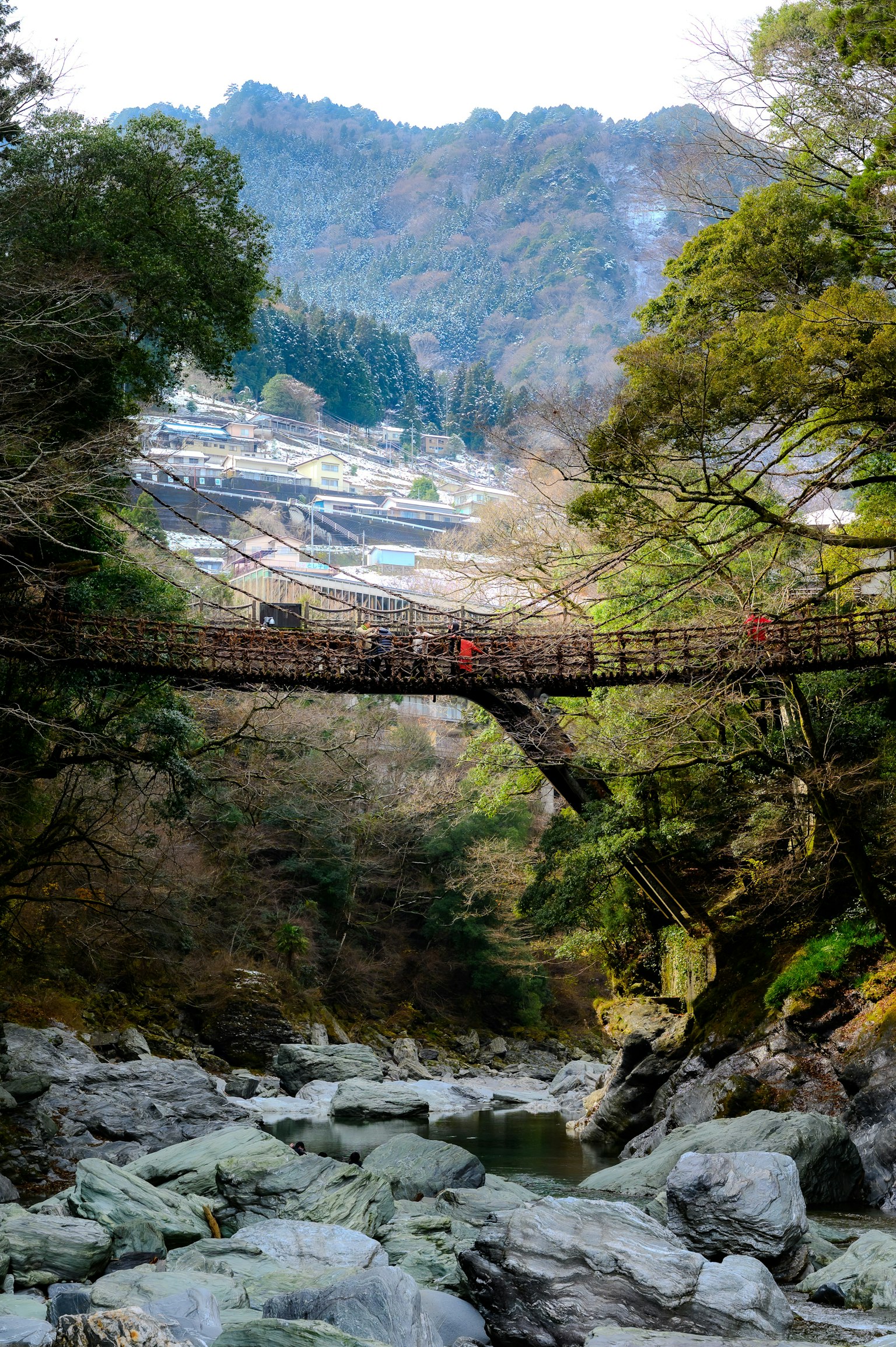 Bellissimo ponte in legno che attraversa un fiume con montagne e vegetazione
