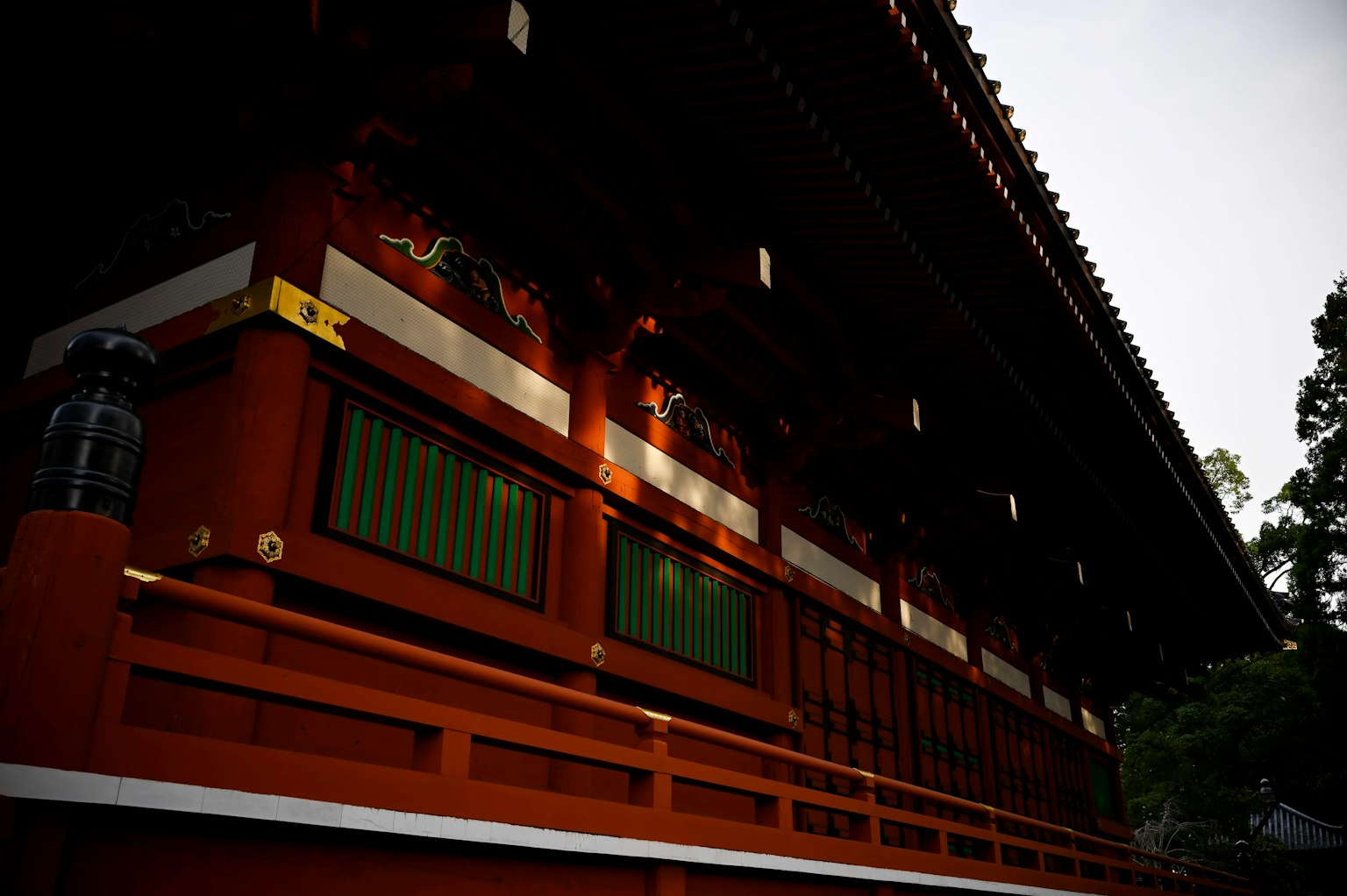 Partie d'un sanctuaire japonais traditionnel avec des murs rouges et des fenêtres vertes