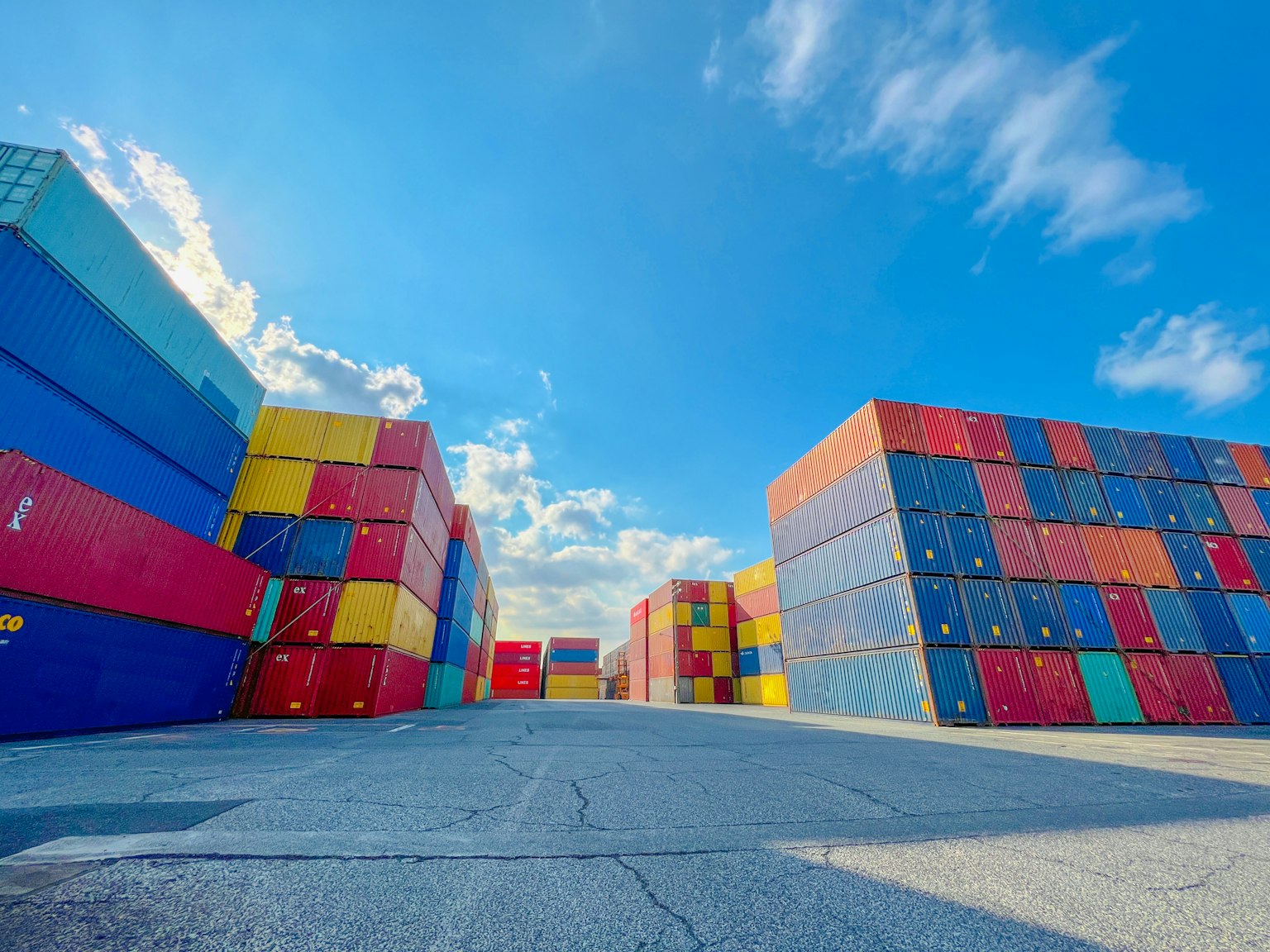 Bunte Versandcontainer in einem Hafen unter einem blauen Himmel mit weißen Wolken