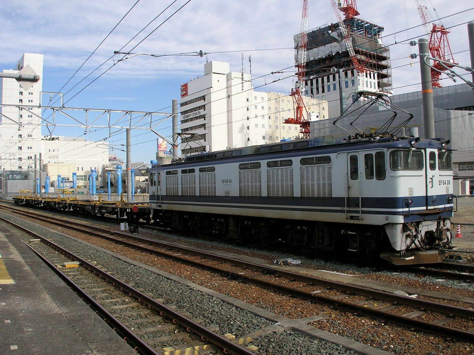 Locomotive électrique bleue et blanche garée sur des voies ferrées dans un environnement urbain