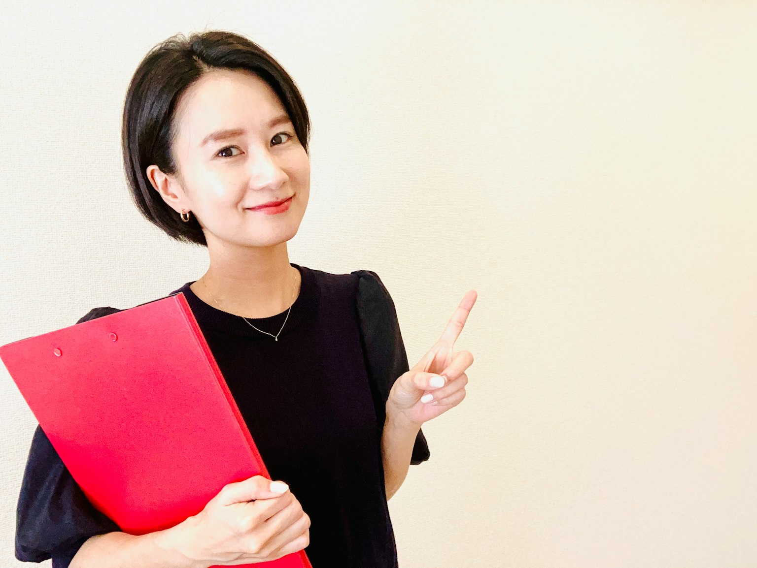Perempuan tersenyum memegang folder merah dengan jari jempol ke atas