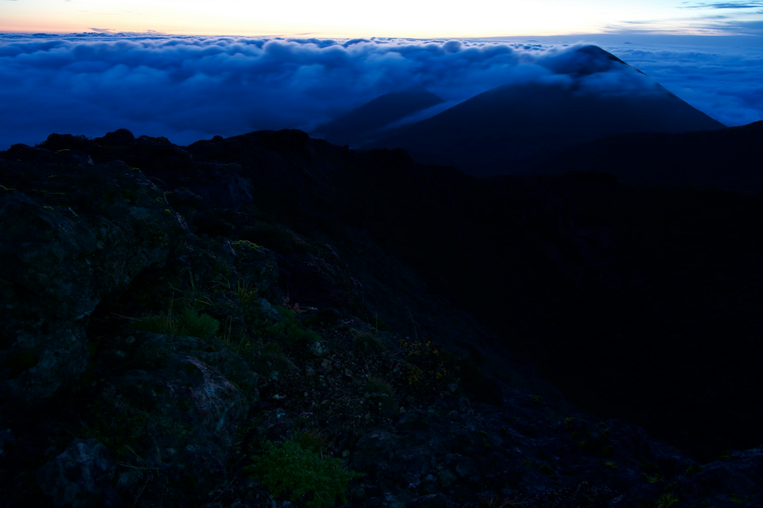 Paisaje montañoso al anochecer con nubes oscuras y picos