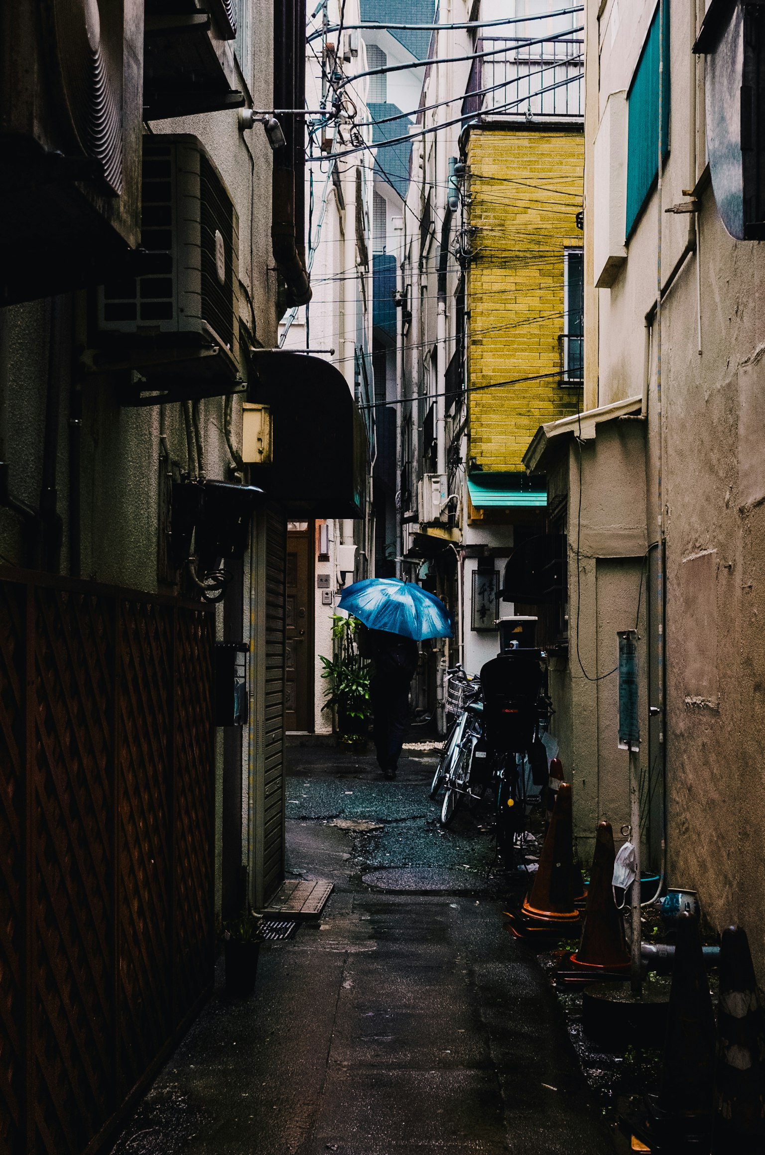 Allée étroite avec une personne tenant un parapluie bleu