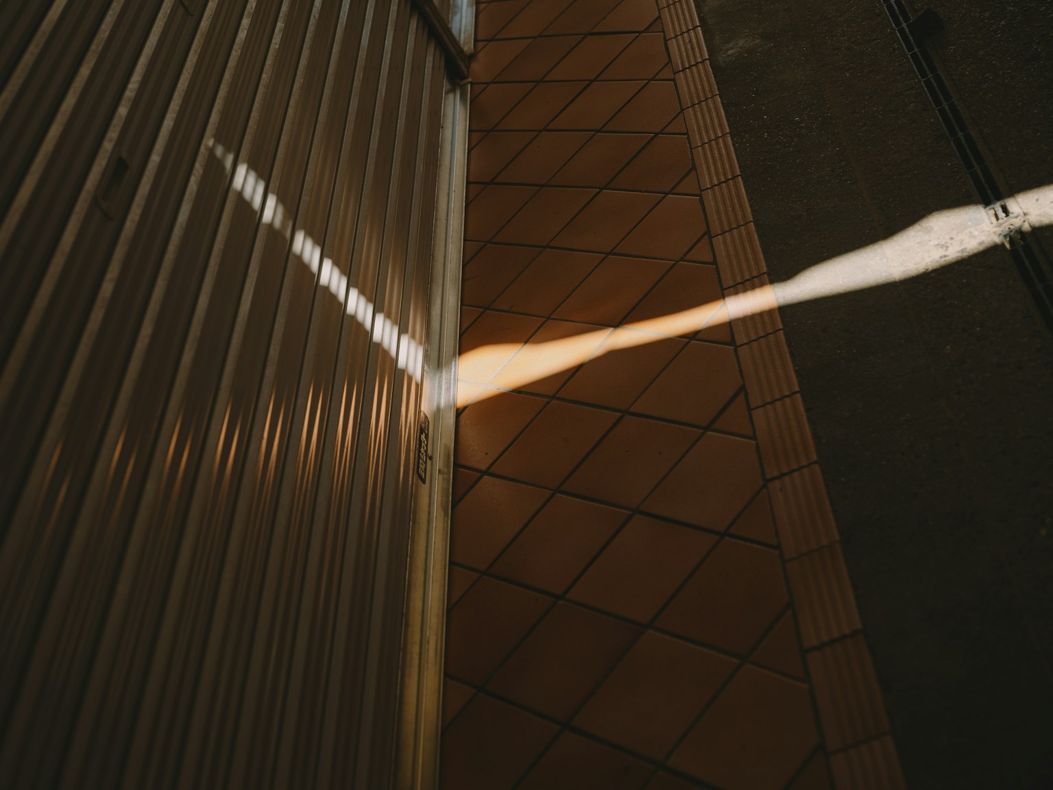 Scene of light reflection on the floor featuring a metal wall and tiled surface