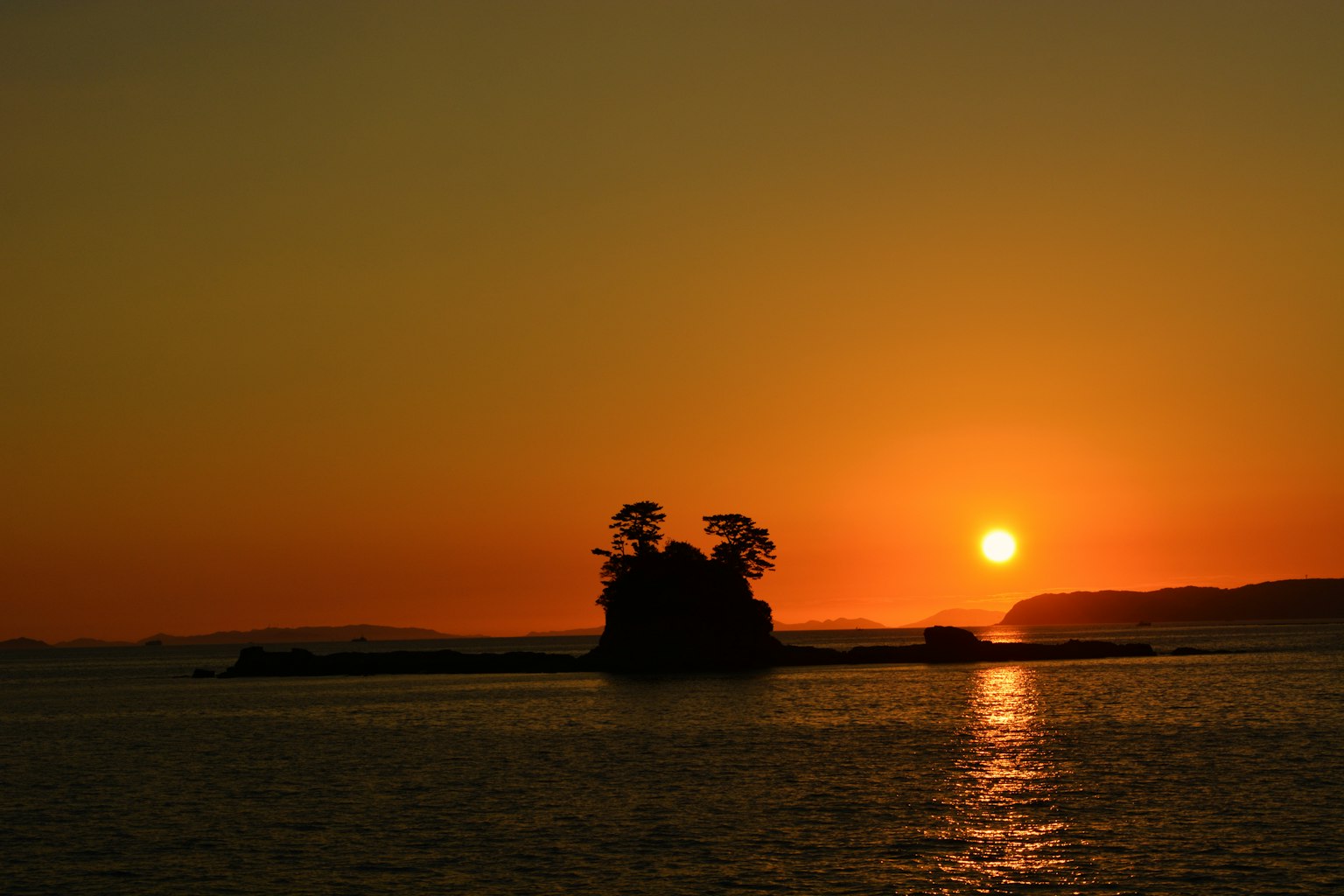 Silhouette einer kleinen Insel gegen einen Sonnenuntergang über dem Meer