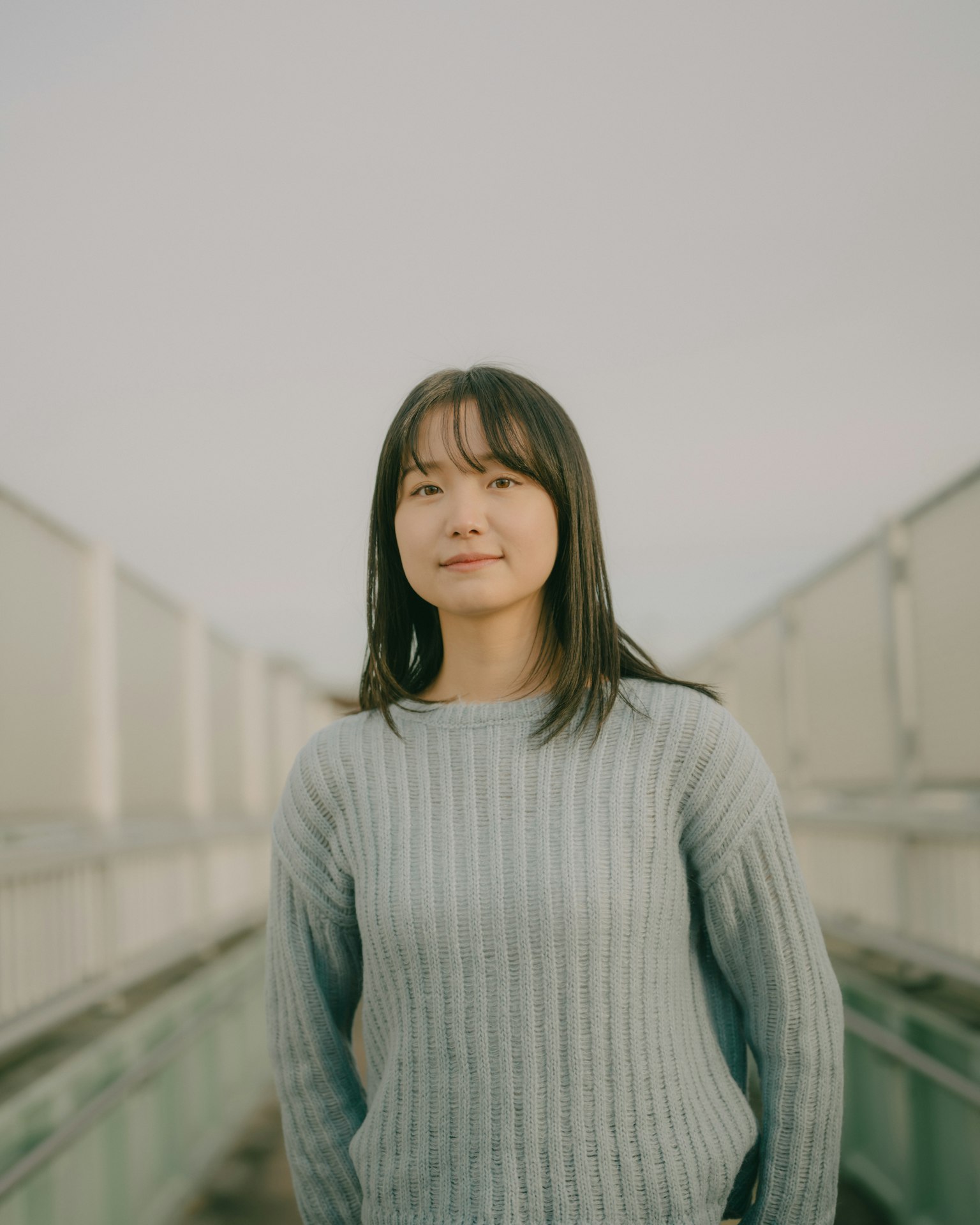 Portrait of a woman smiling on a rooftop wearing a blue sweater