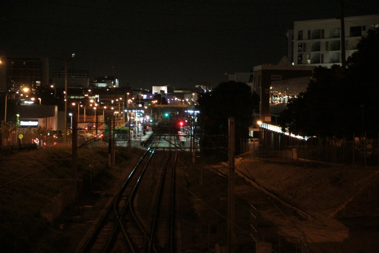 ทิวทัศน์เมืองยามค่ำคืนที่มีรางรถไฟและแสงไฟในเมือง