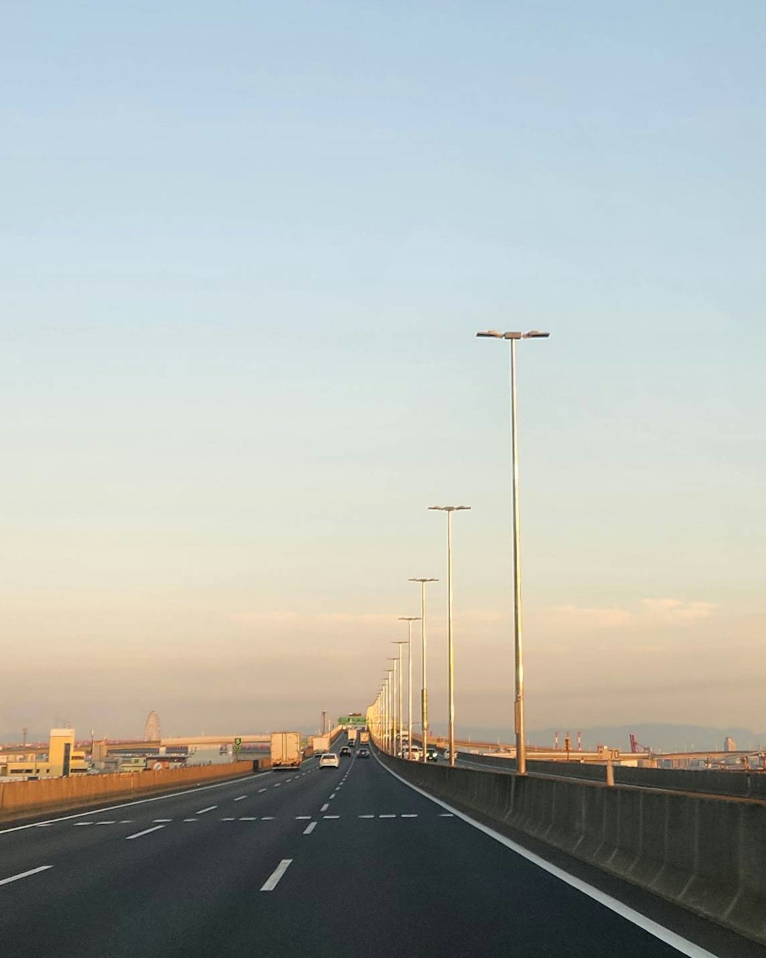 Eine lange Straße unter einem blauen Himmel mit Straßenlaternen an den Seiten