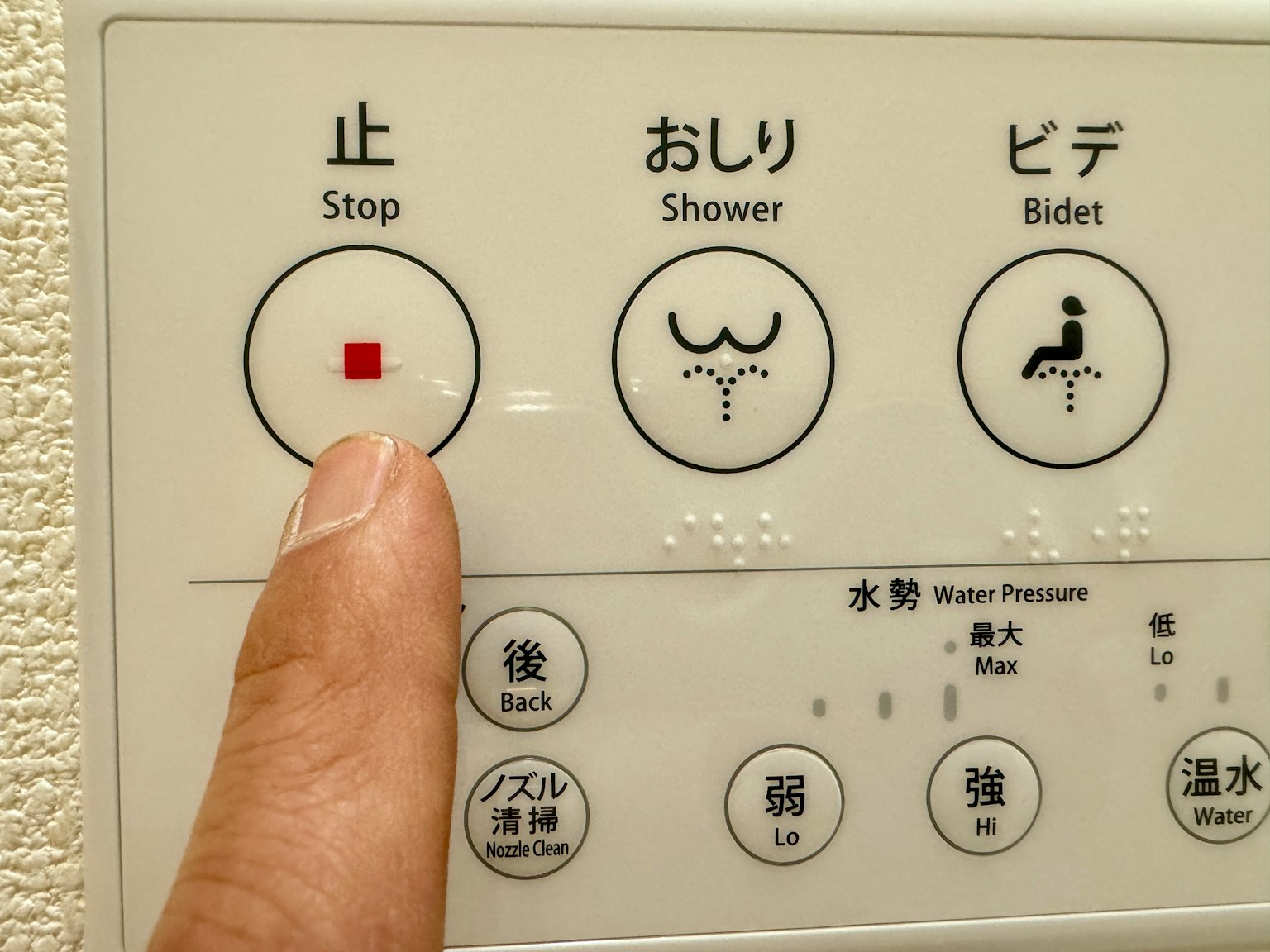 手指触摸厕所控制面板，红色停止按钮突出显示