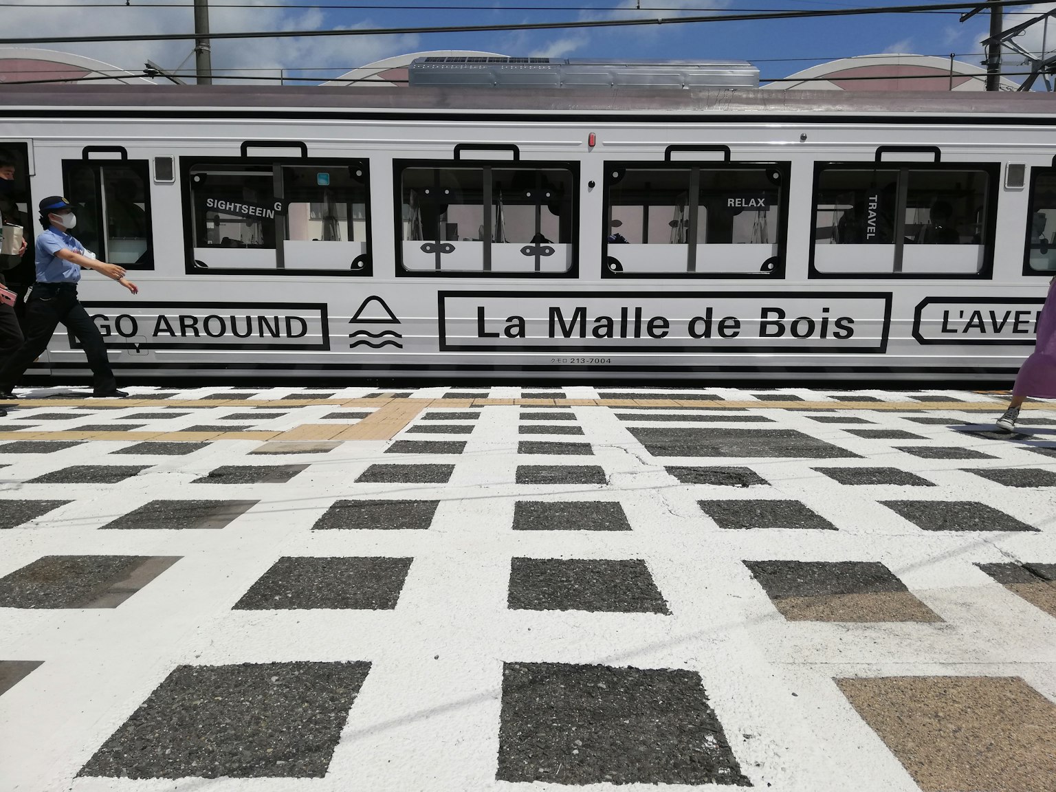 Tram with white and black checkered pavement visible The tram features the text La Malle de Bois and GO AROUND