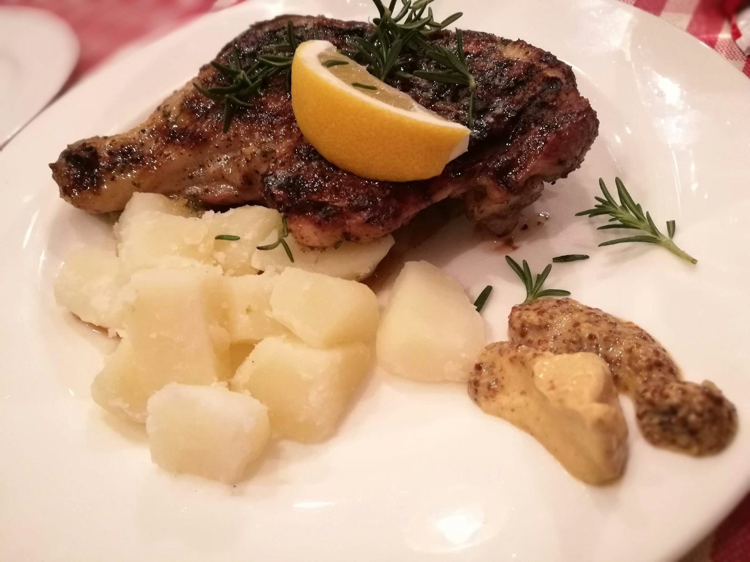 Coscia di pollo grigliata guarnita con limone e rosmarino servita con patate e senape