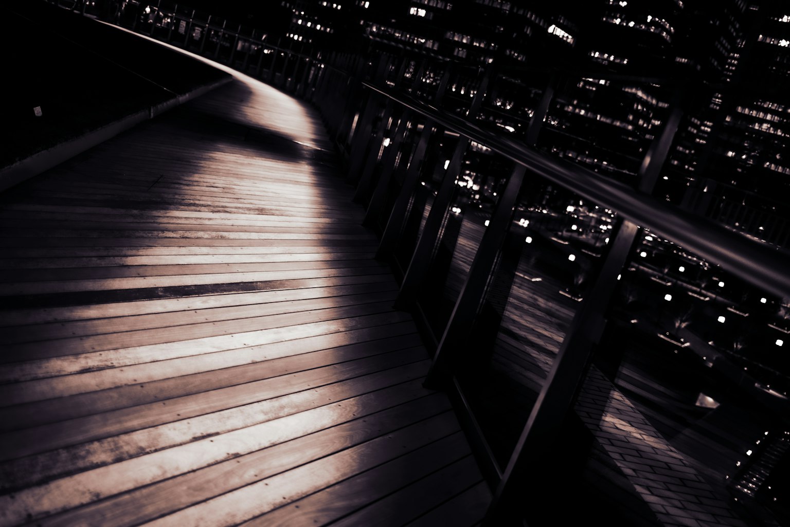 ภาพทางเดินไม้ที่มีทิวทัศน์เมืองในตอนกลางคืน