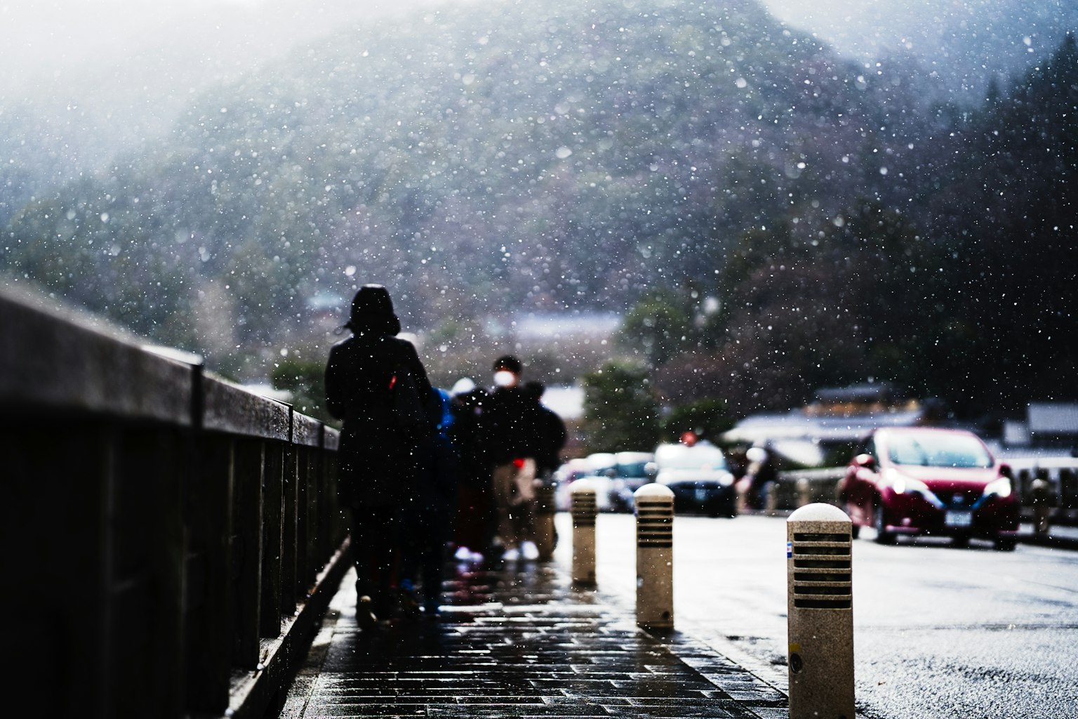 在降雪中站在桥上的人和山的背景