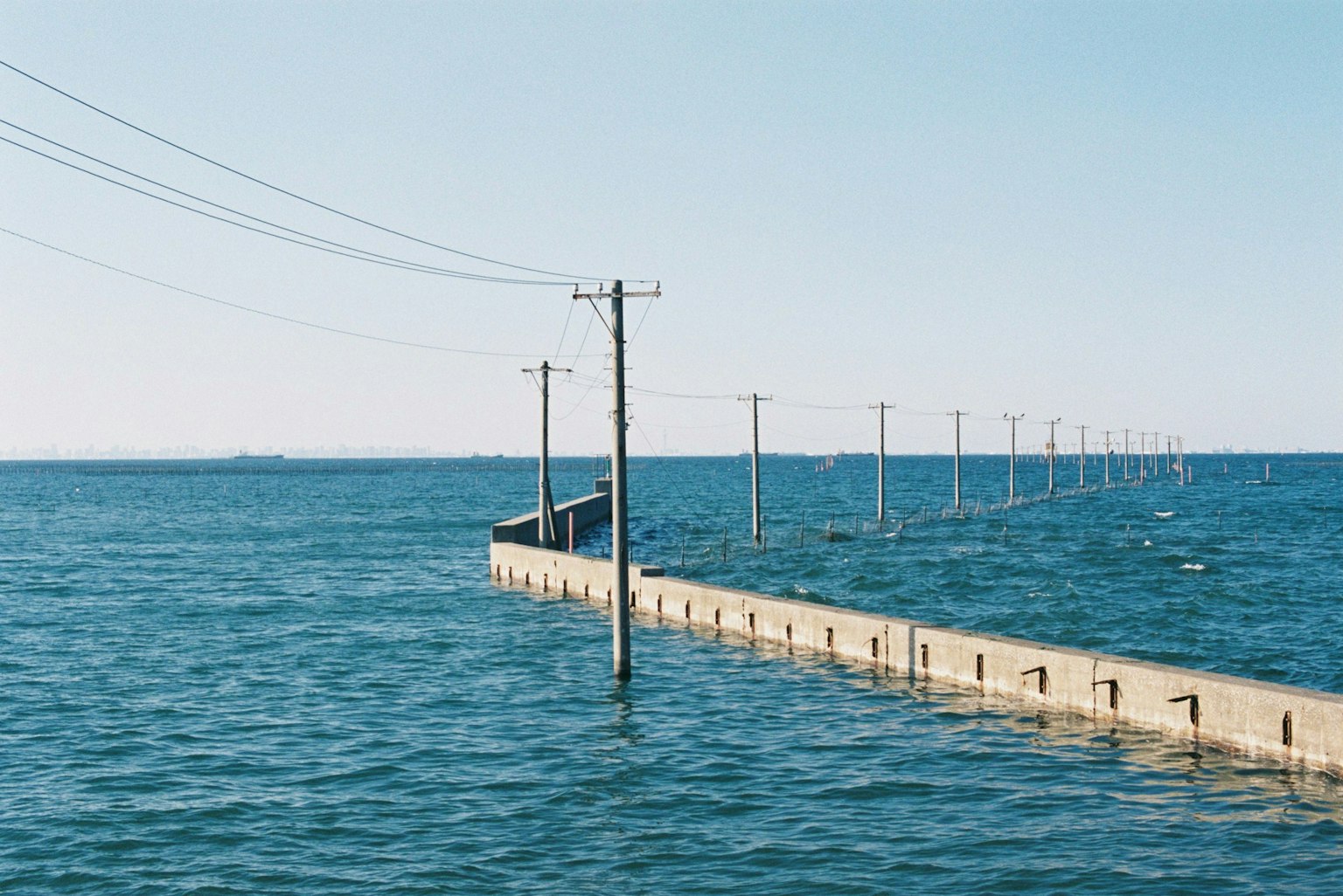 Utility poles extending over the water with a concrete pier