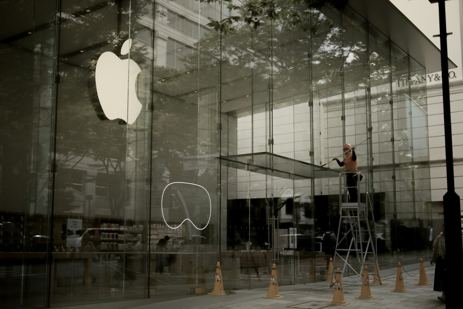 Persona limpiando la fachada de vidrio de una tienda Apple con el logo icónico visible