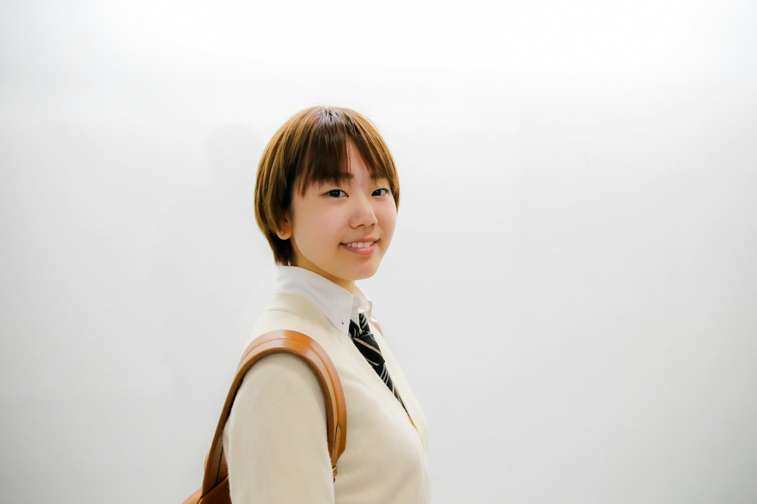 흰색 배경 앞에서 미소 짓고 있는 젊은 여성의 초상